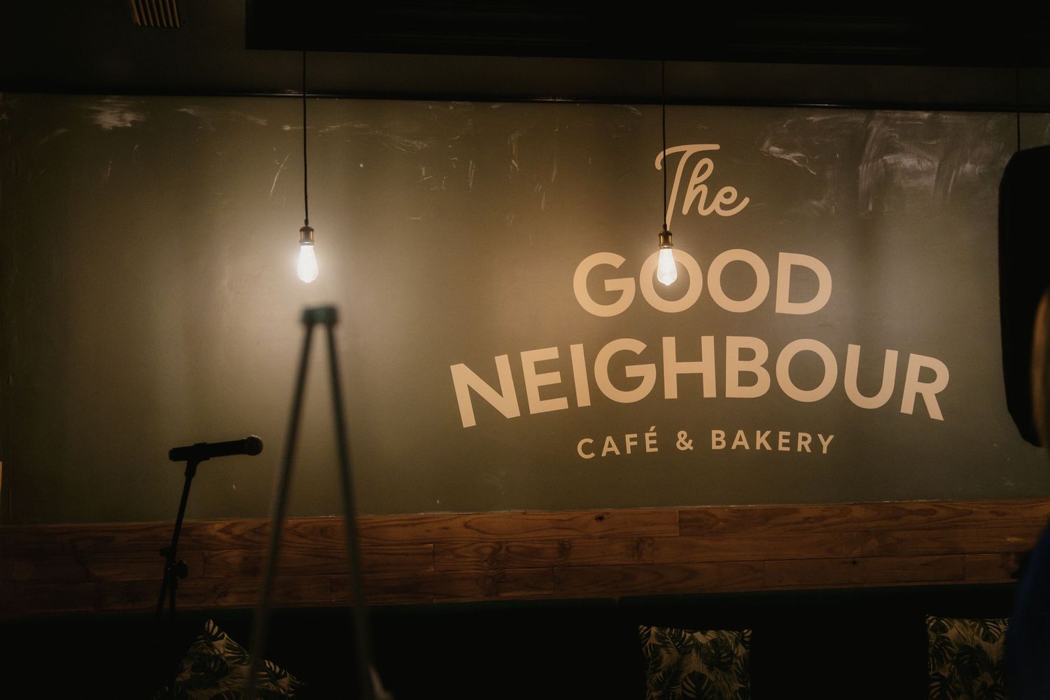 A dimly lit cafe exterior with illuminated signage reading 'Good Neighbor' at night.