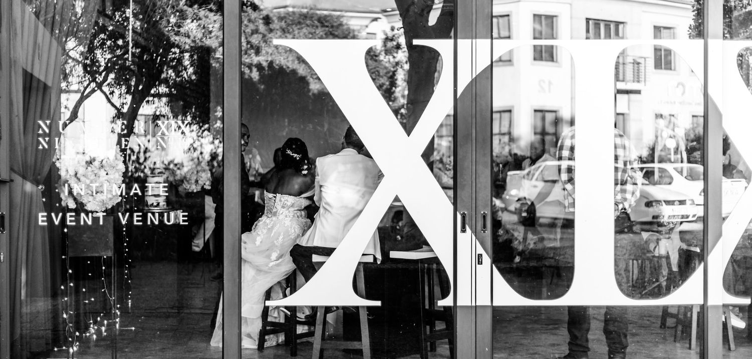 Black and white photograph of a storefront window with large X letters visible in the window display.