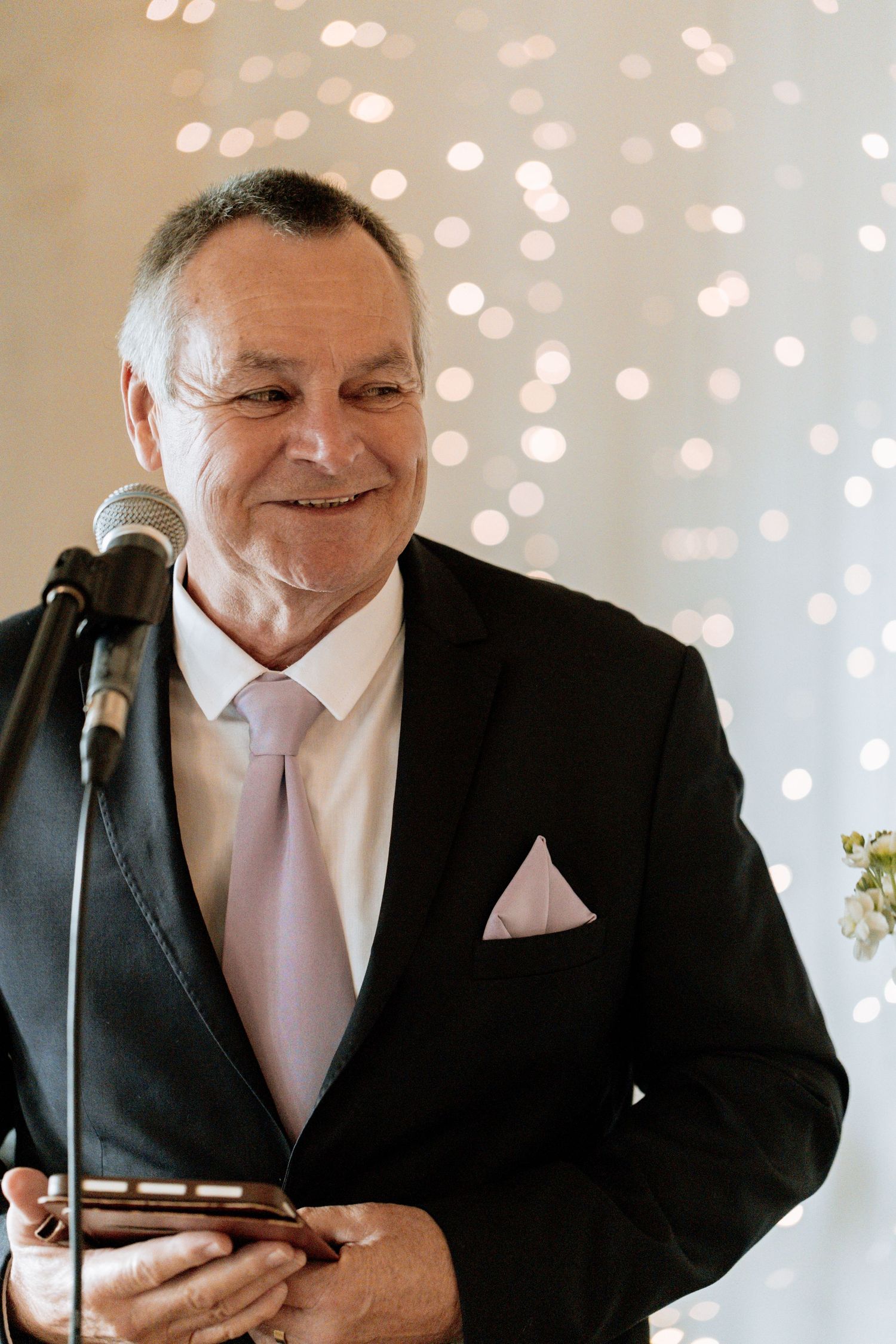 A series of candid reactions taken from someone in a black suit and pink tie giving a speech against a light background.