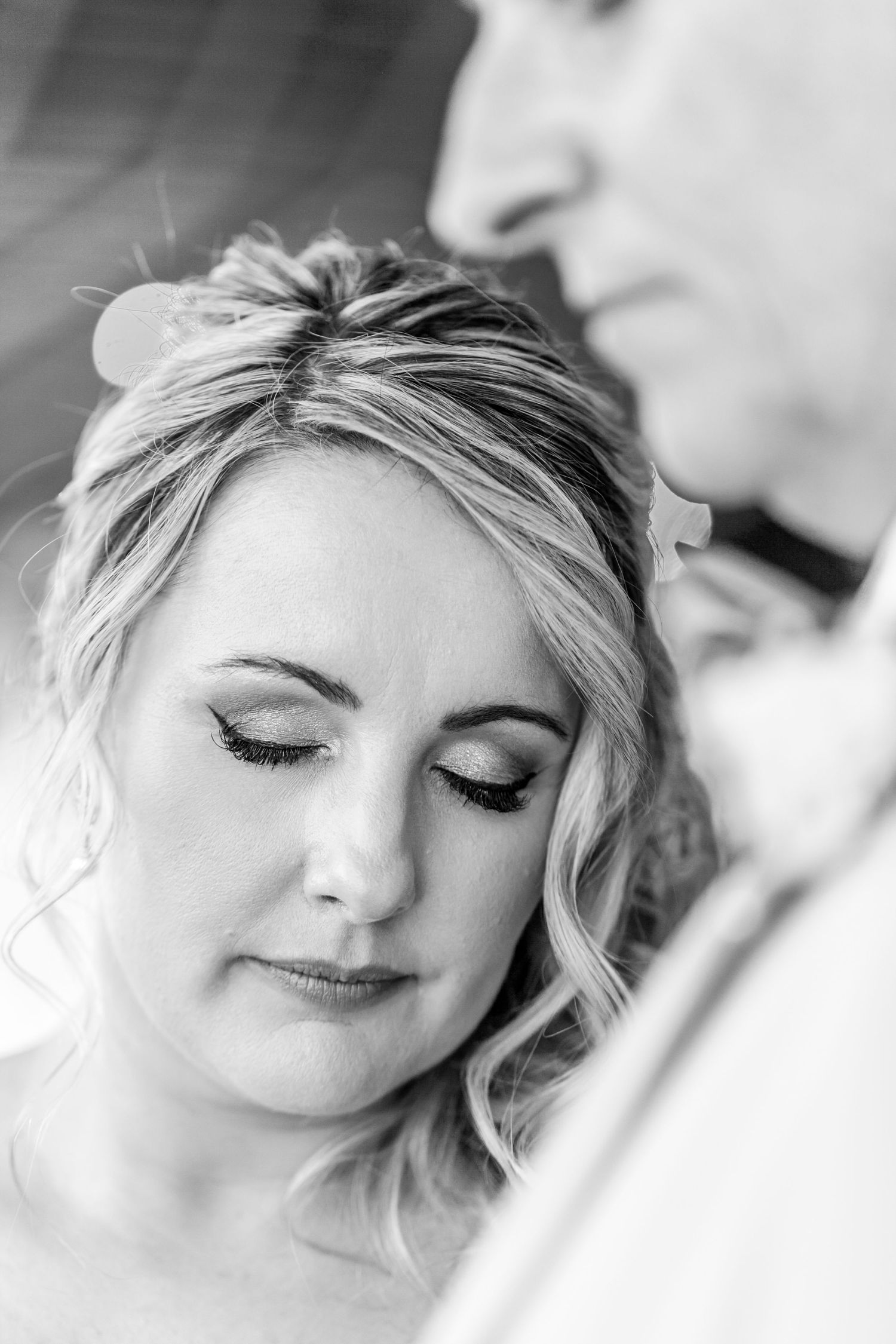 Black and white close-up portrait of a serene bride with closed eyes and softly styled blonde hair.