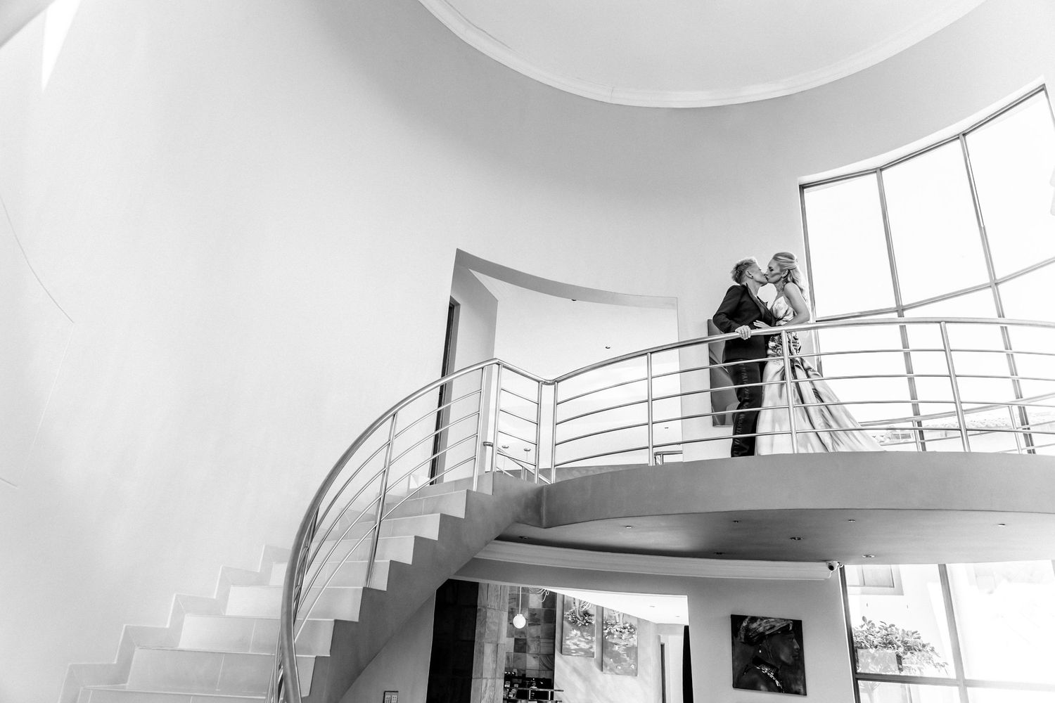 A modern white interior space with curved architectural features and railings shows a minimalist design aesthetic.