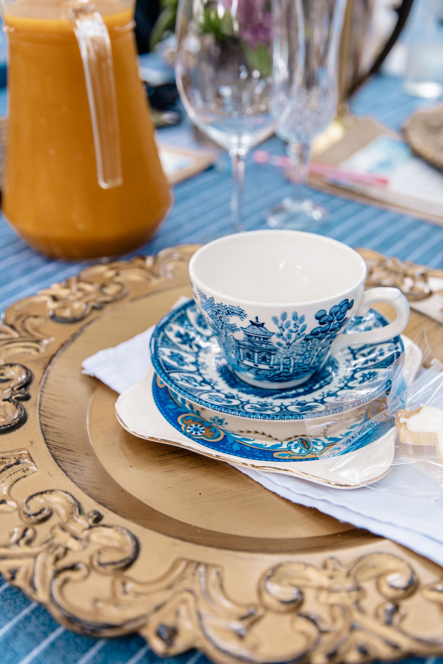 A vintage blue and white china teacup and saucer set displayed on an ornate gold charger plate.