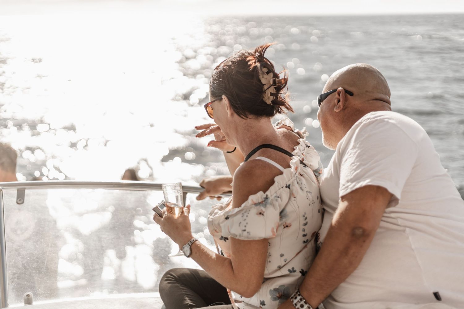 A couple laughing together on a boat deck during sunset on the ocean.