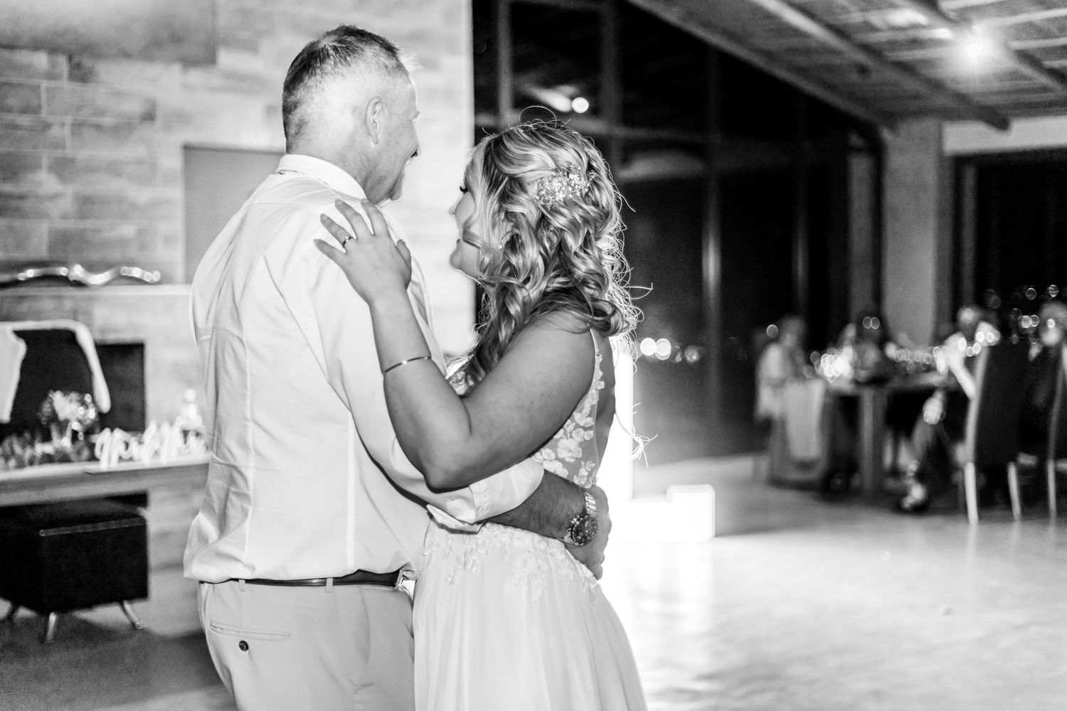 A black and white photograph of couples dancing together in an indoor venue during a celebration.