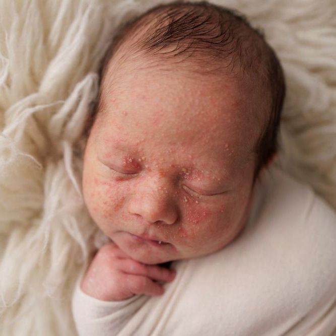 Newborn baby sleeping soundly on soft cream colored blanket.