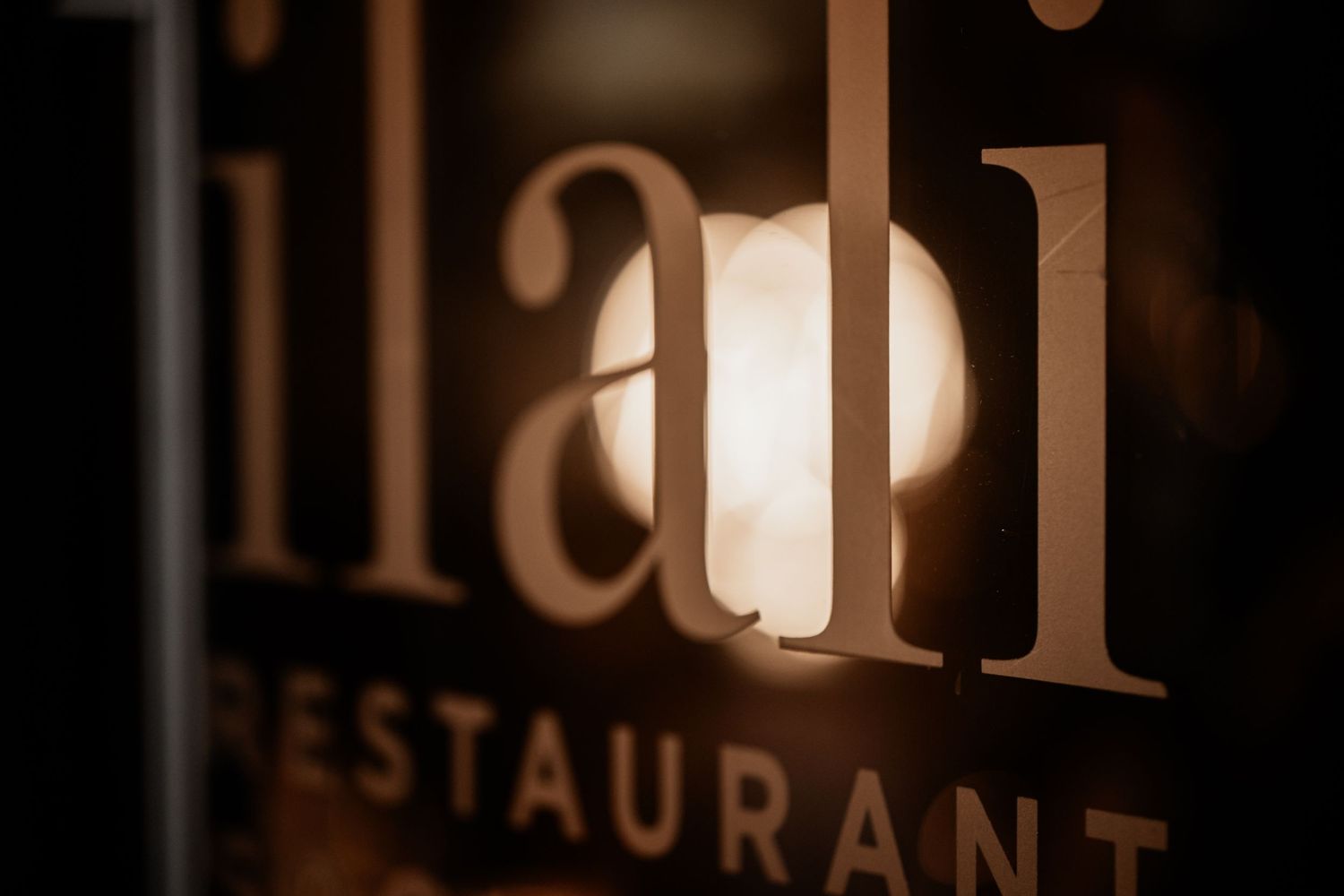 Close-up view of illuminated restaurant signage with soft bokeh lighting effect in the background.
