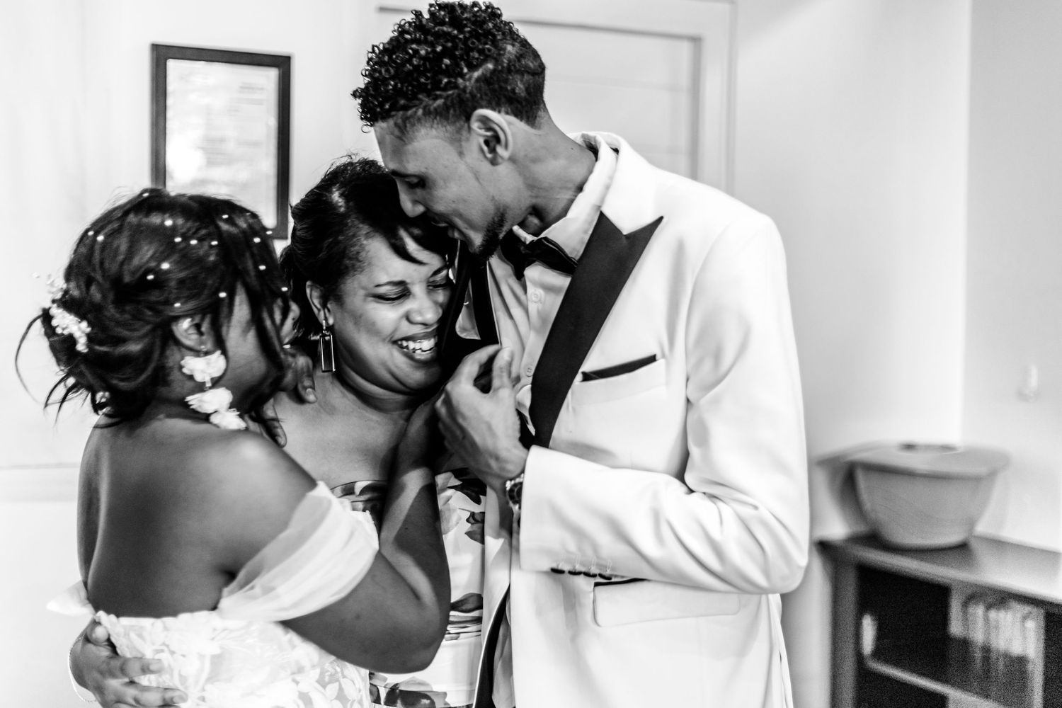 A couple in wedding attire shares an intimate moment with arms wrapped around each other in black and white.