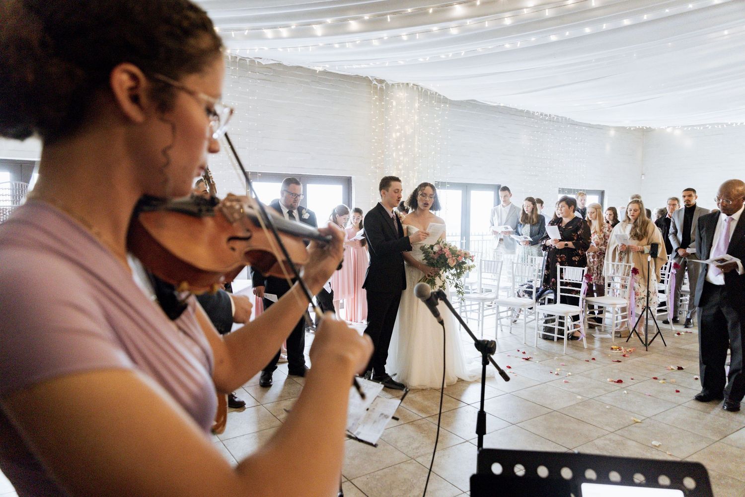 A photographer captures events through a camera lens at a wedding reception venue with decorative lighting.