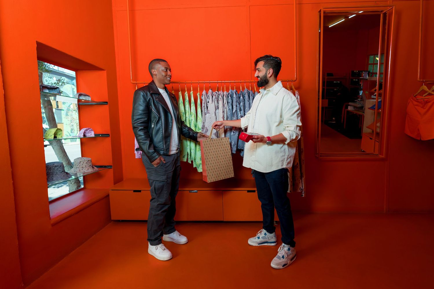 Students collaborate in an orange-painted hallway with mounted artwork displayed along the wall.