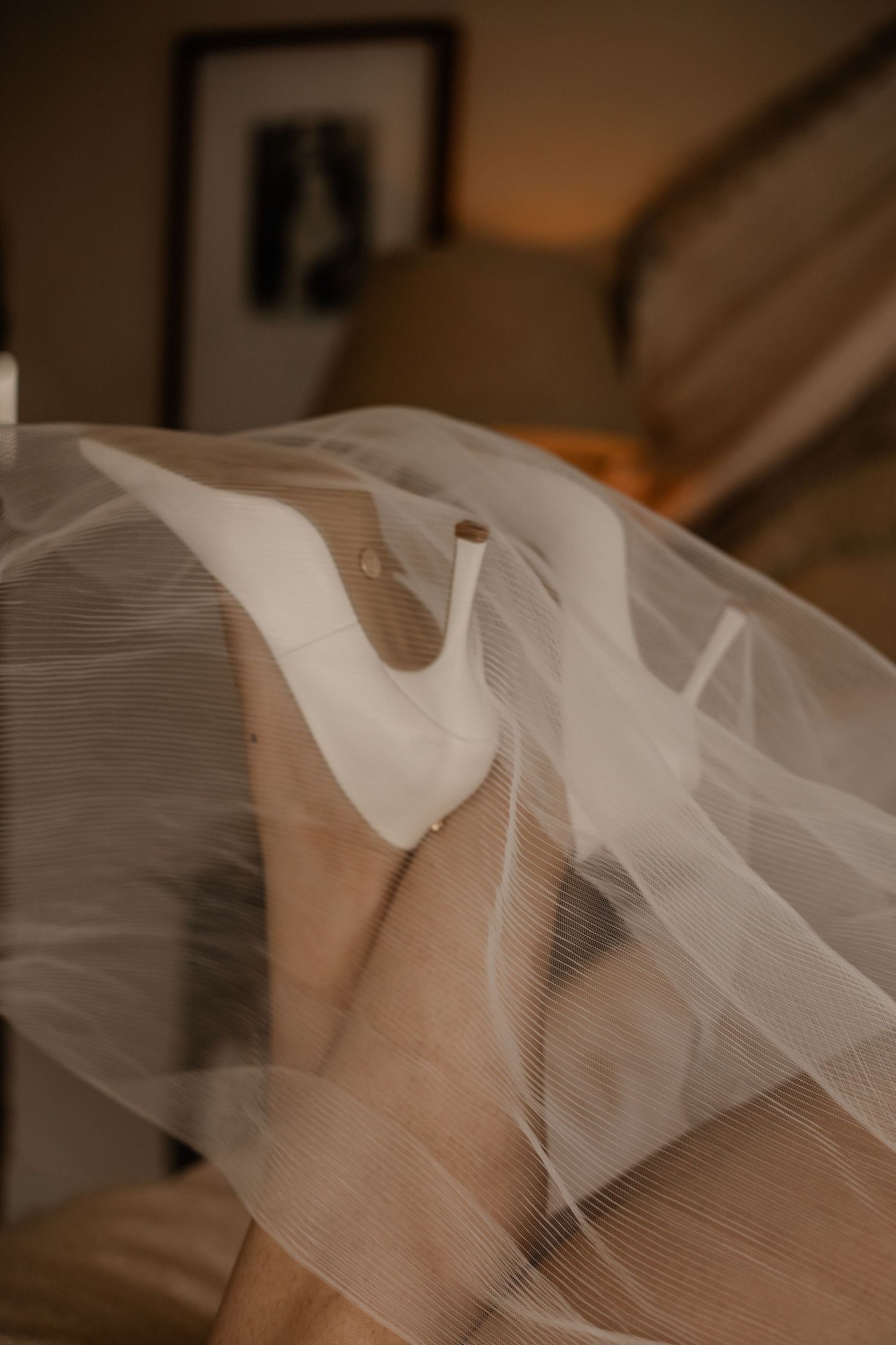 Delicate white tulle veil fabric creates soft flowing waves and folds in warm lighting.