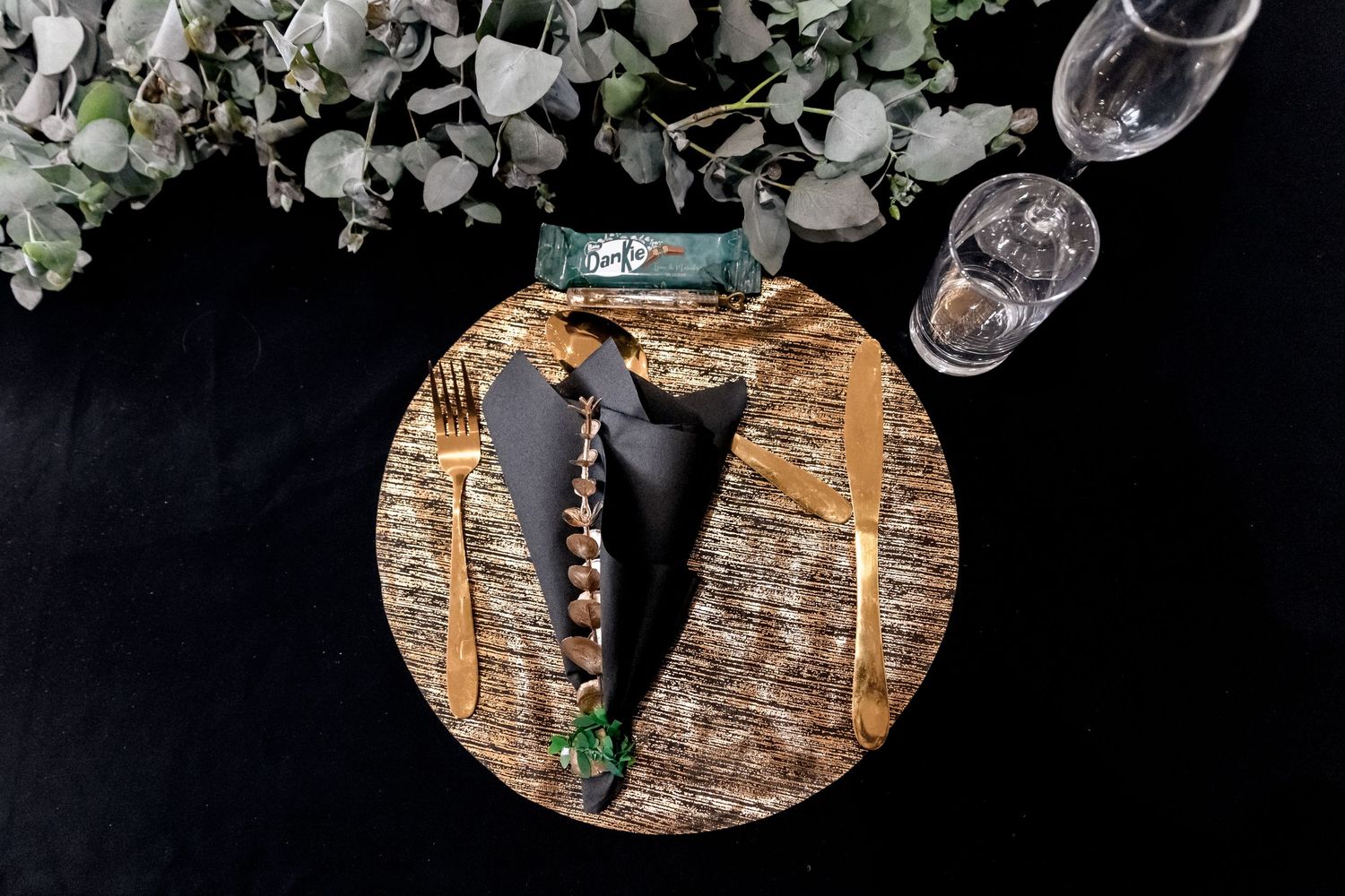 Wine glasses and bottles arranged with rustic wooden decor and greenery for an elegant table setting.