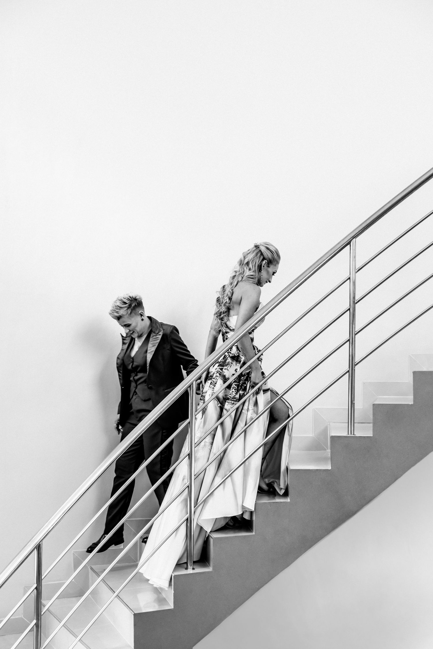 A sequence of black and white photos showing people walking up a minimalist staircase with white railings.