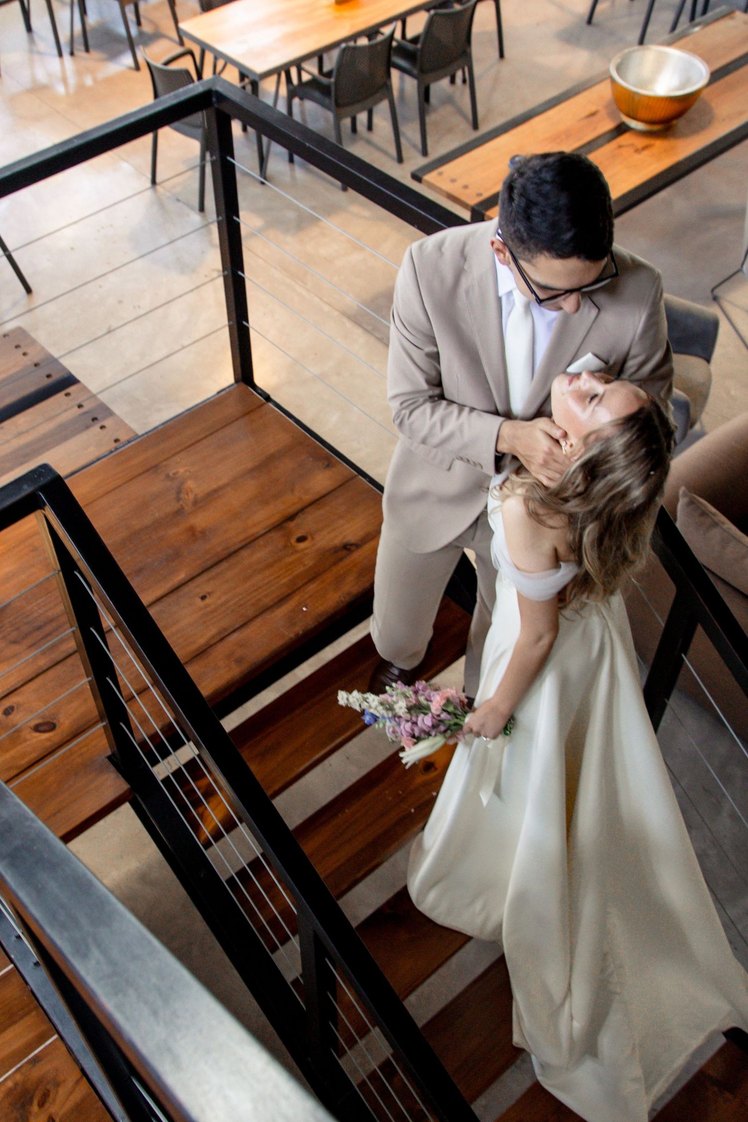 A romantic couple shares intimate moments in a rustic restaurant setting with wooden tables and benches.