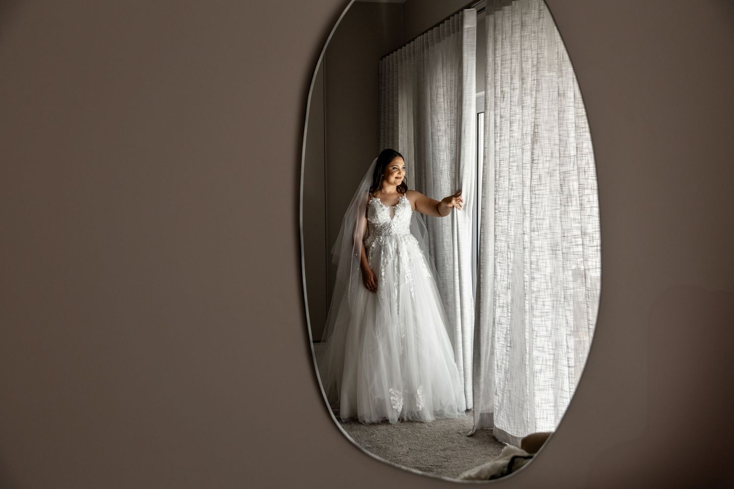 Sequence of bride portraits in wedding gown with soft window light and oval mirror reflections creating romantic ambiance.