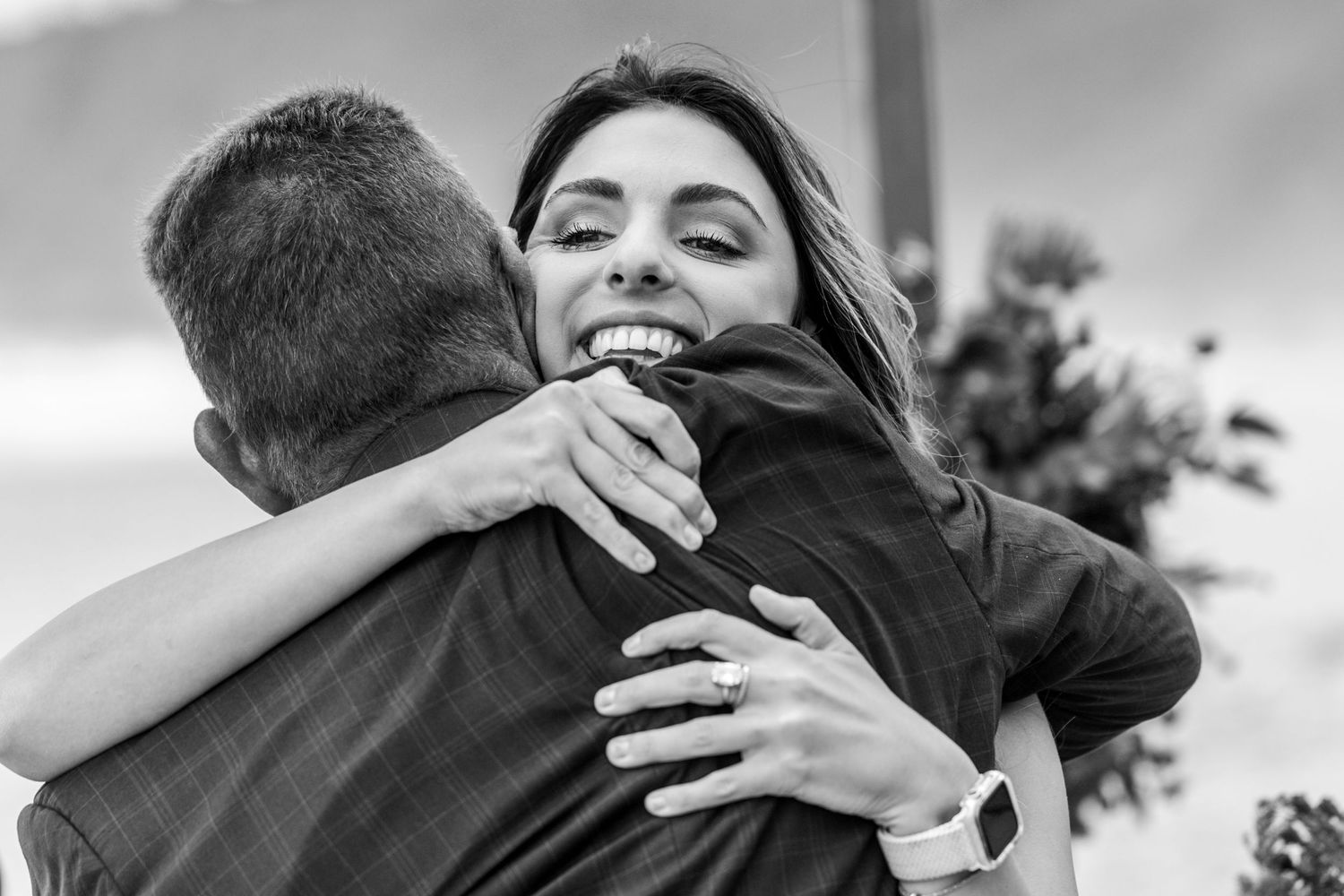 Black and white photo of two people sharing a joyful embrace outdoors.