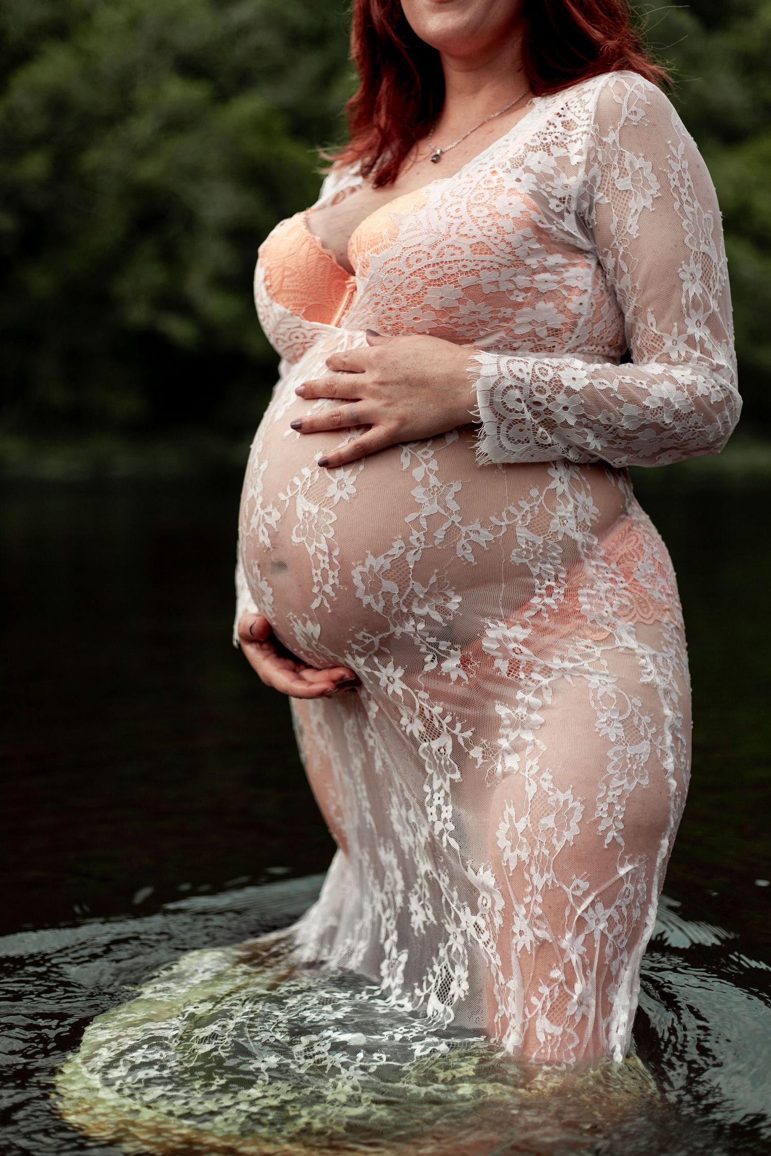 A lace maternity dress photoshoot featuring a woman standing in water outdoors.