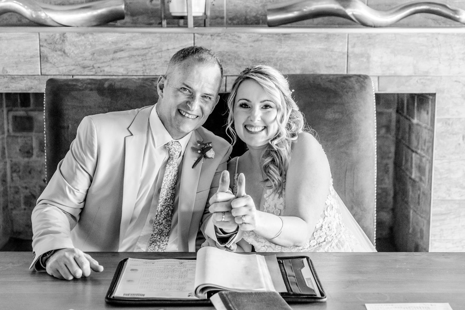 A black and white photo of newlyweds celebrating with drinks at a reception venue.
