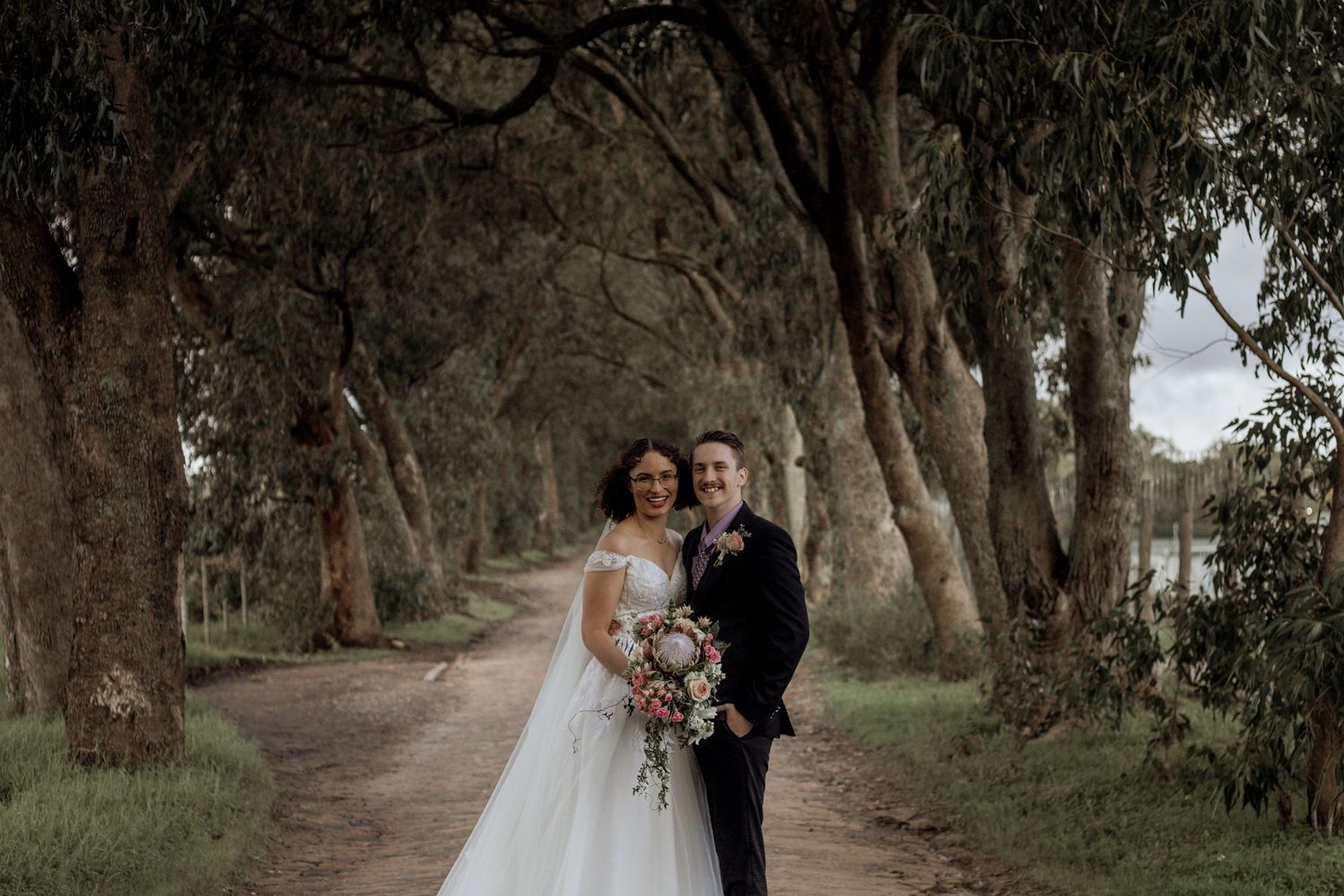 A couple shares an intimate moment under a canopy of towering eucalyptus trees during their wedding day.