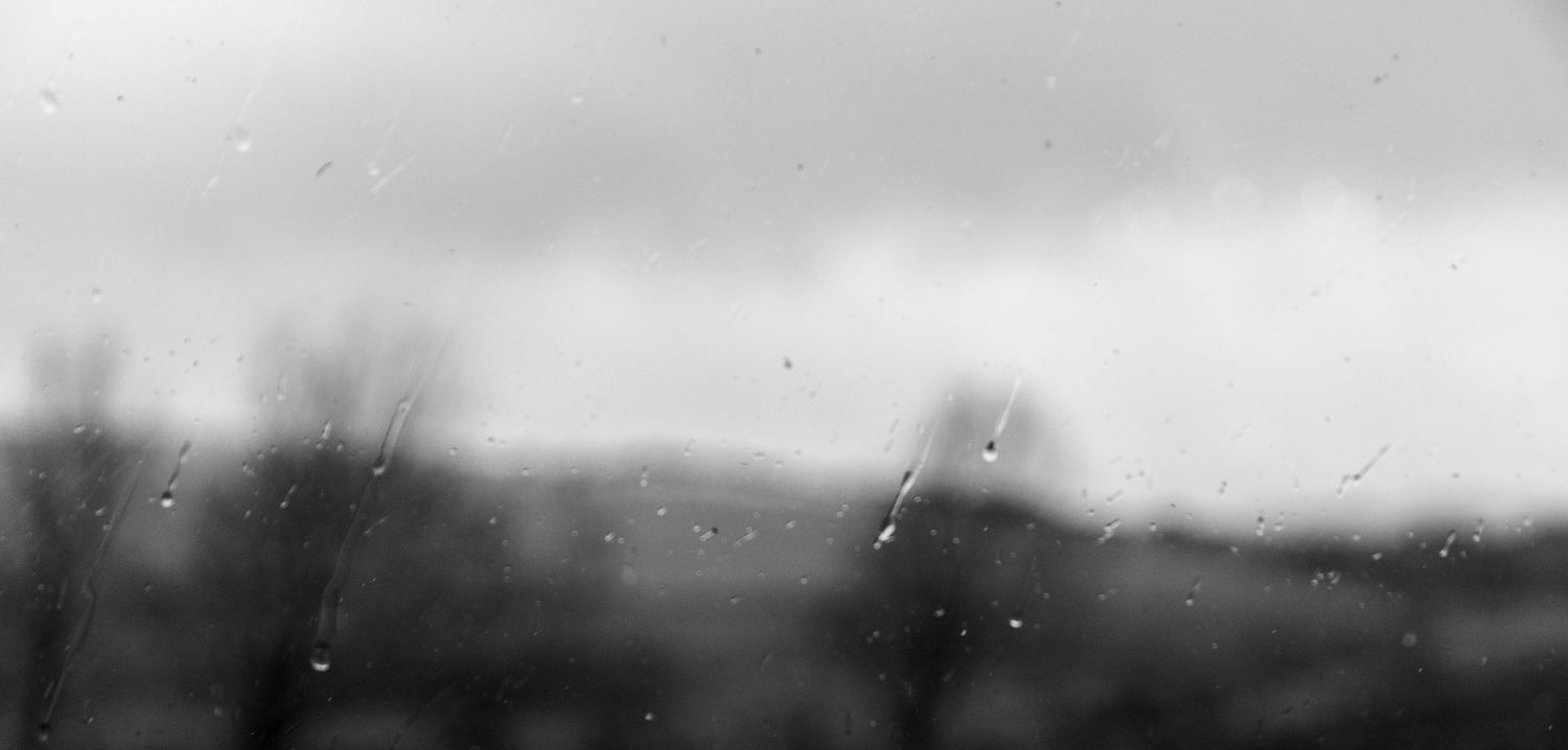 Black and white panoramic photograph of farm fields with storm clouds gathering on the horizon.