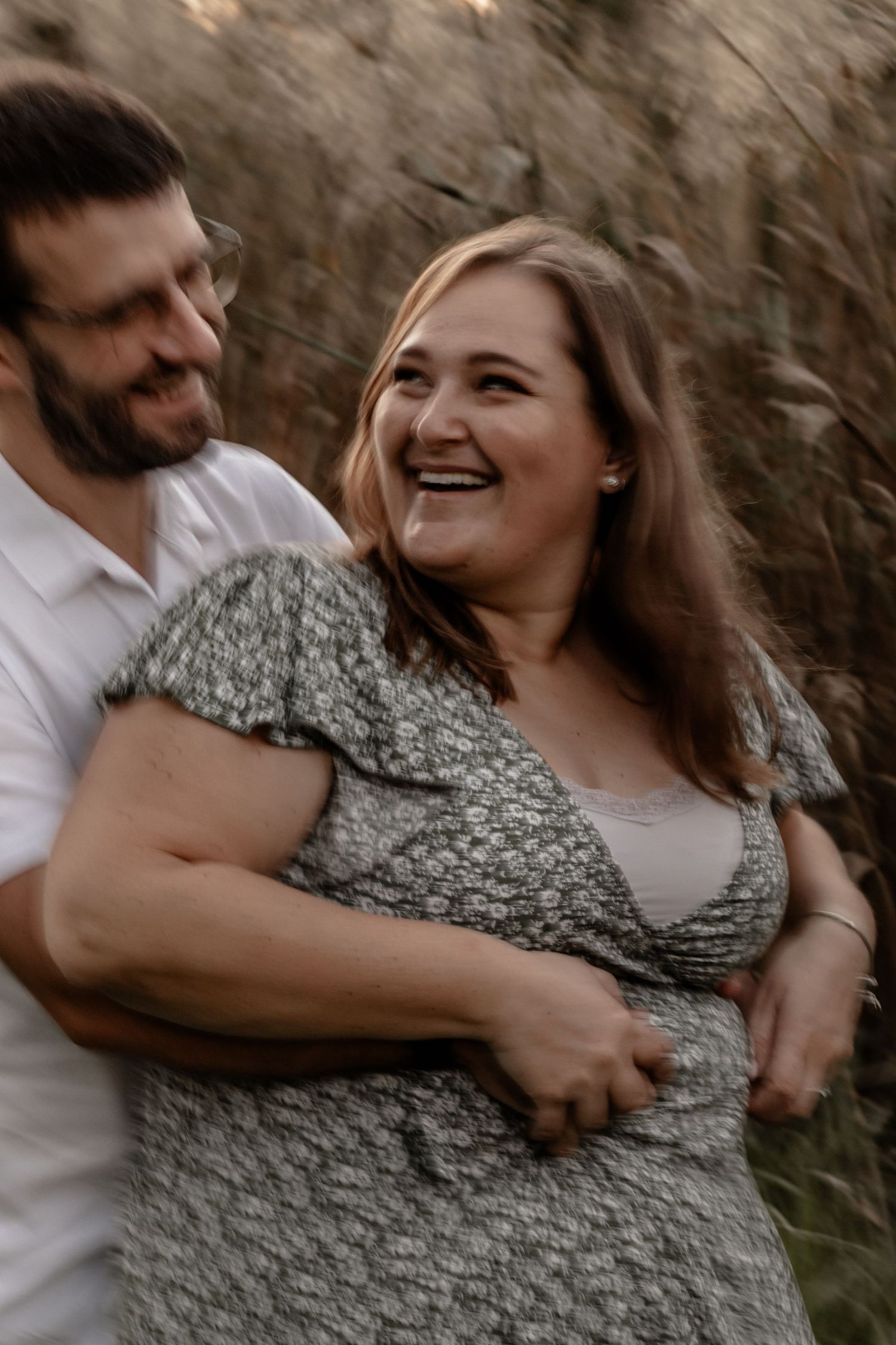 A couple shares a tender embrace outdoors during a romantic photoshoot at golden hour.