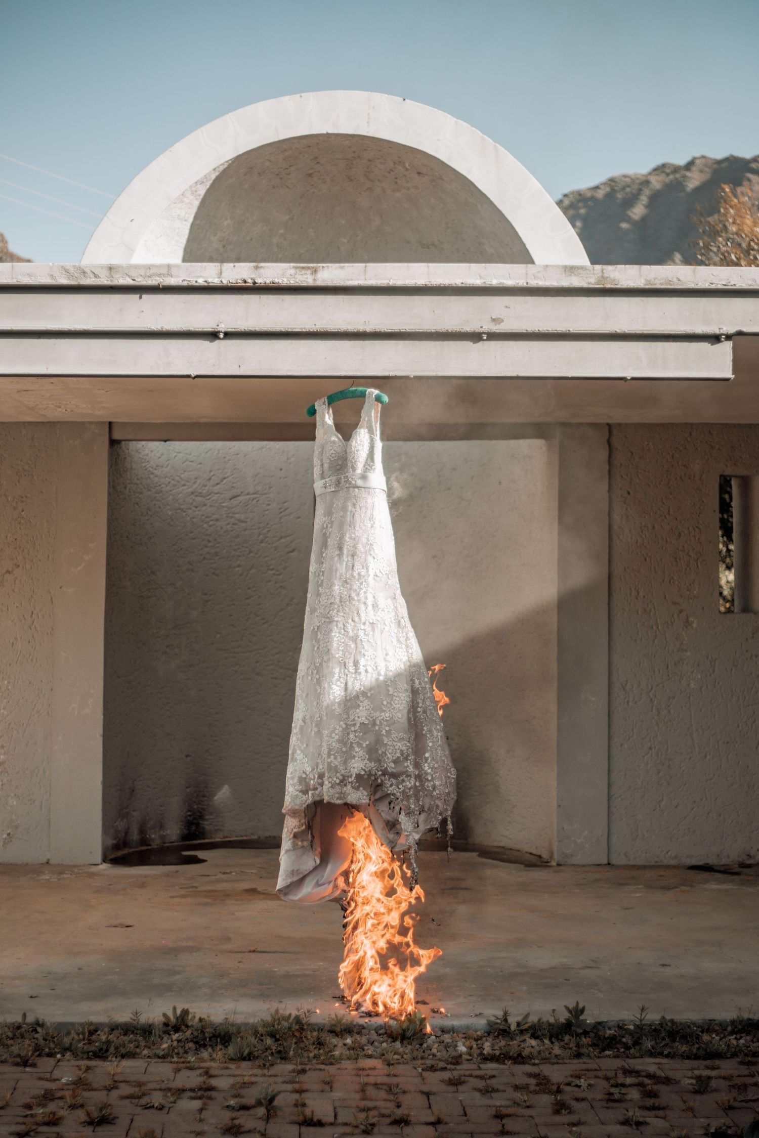A time-lapse sequence shows a white sculptural form bursting into flames against a concrete wall backdrop.