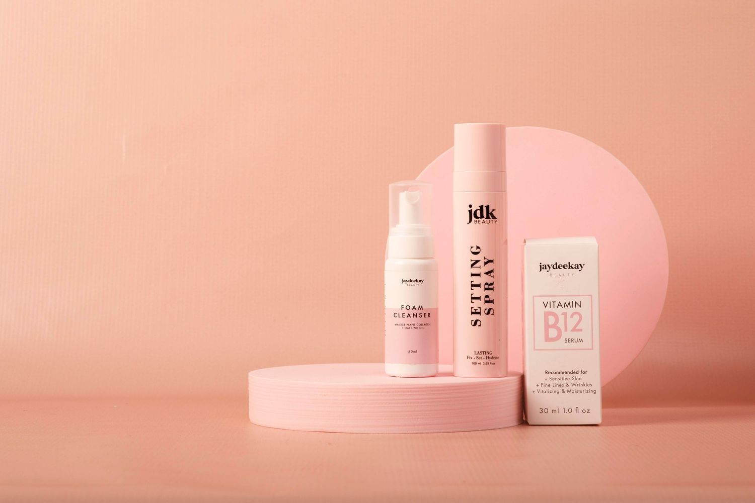 Minimalist pink beauty product bottles arranged in a gradient lineup against a soft coral background.