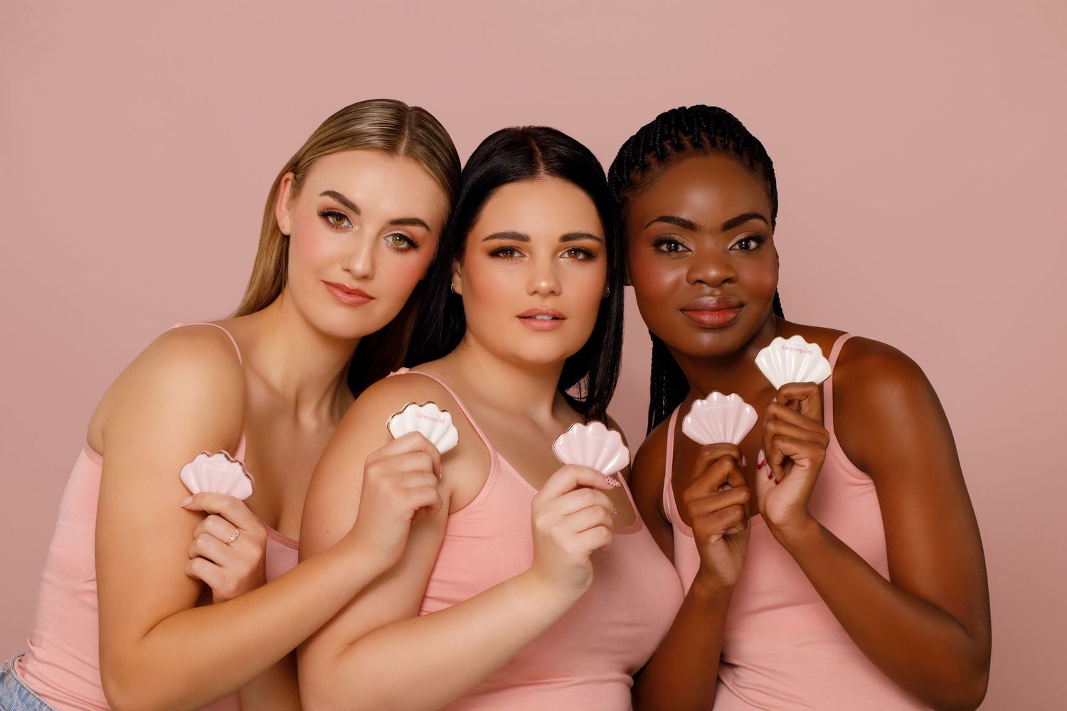 Three friends in pink dresses hold ice cream cones against a pink background.