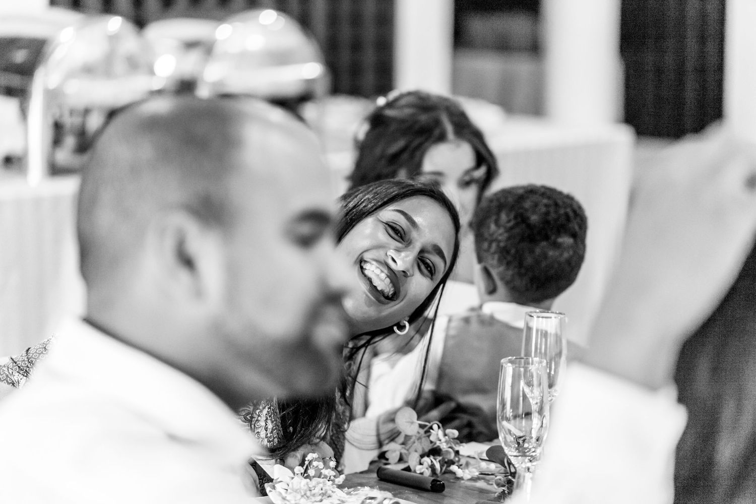 A black and white collage of candid moments from a wedding reception celebration shows dancing and laughter.