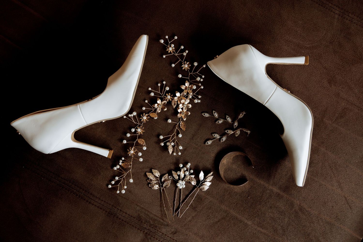 High heel shoes arranged artistically with scattered gold glitter on dark brown textured background.