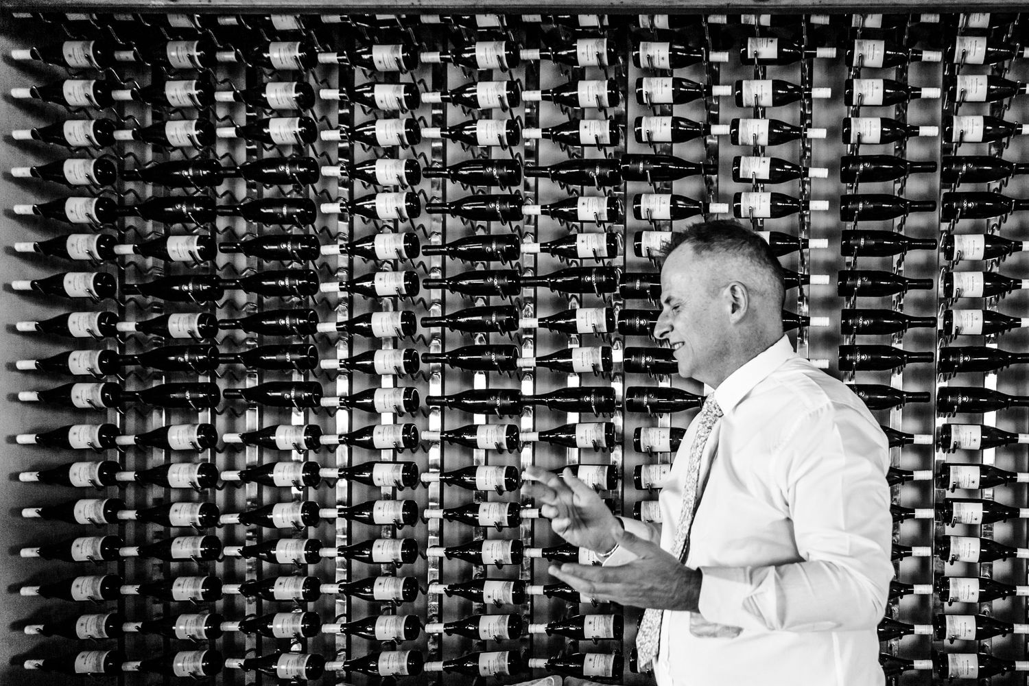 A man in a white shirt examines equipment in a room full of vintage computer or telephone switchboard panels.