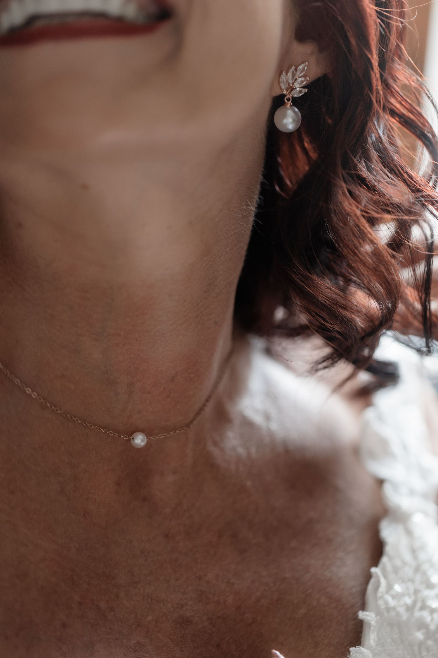 Delicate silver necklace with a small pearl pendant adorning someone's neckline in a close-up shot.