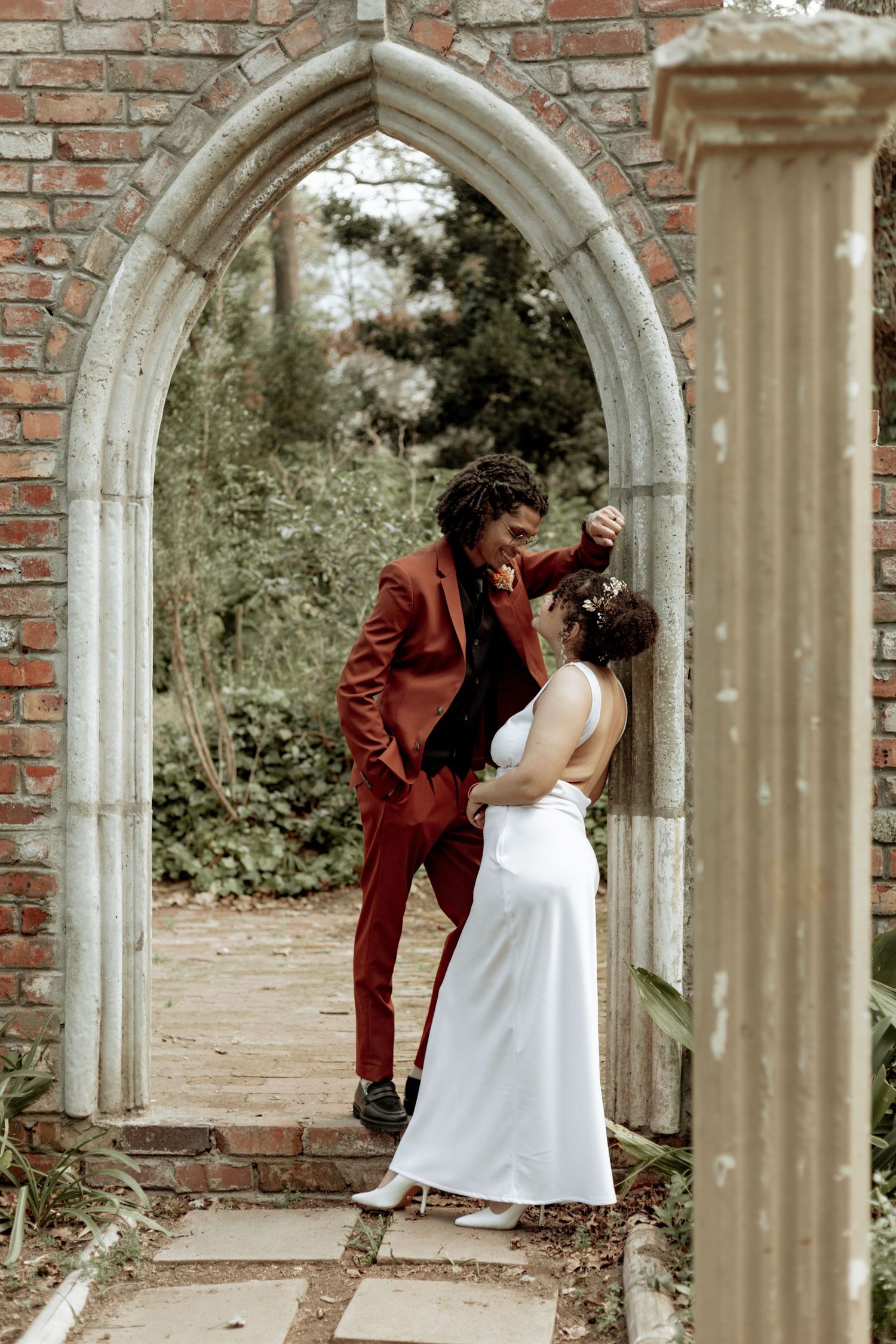 Three romantic wedding photos showing a couple dancing and embracing under stone archways of a brick building.