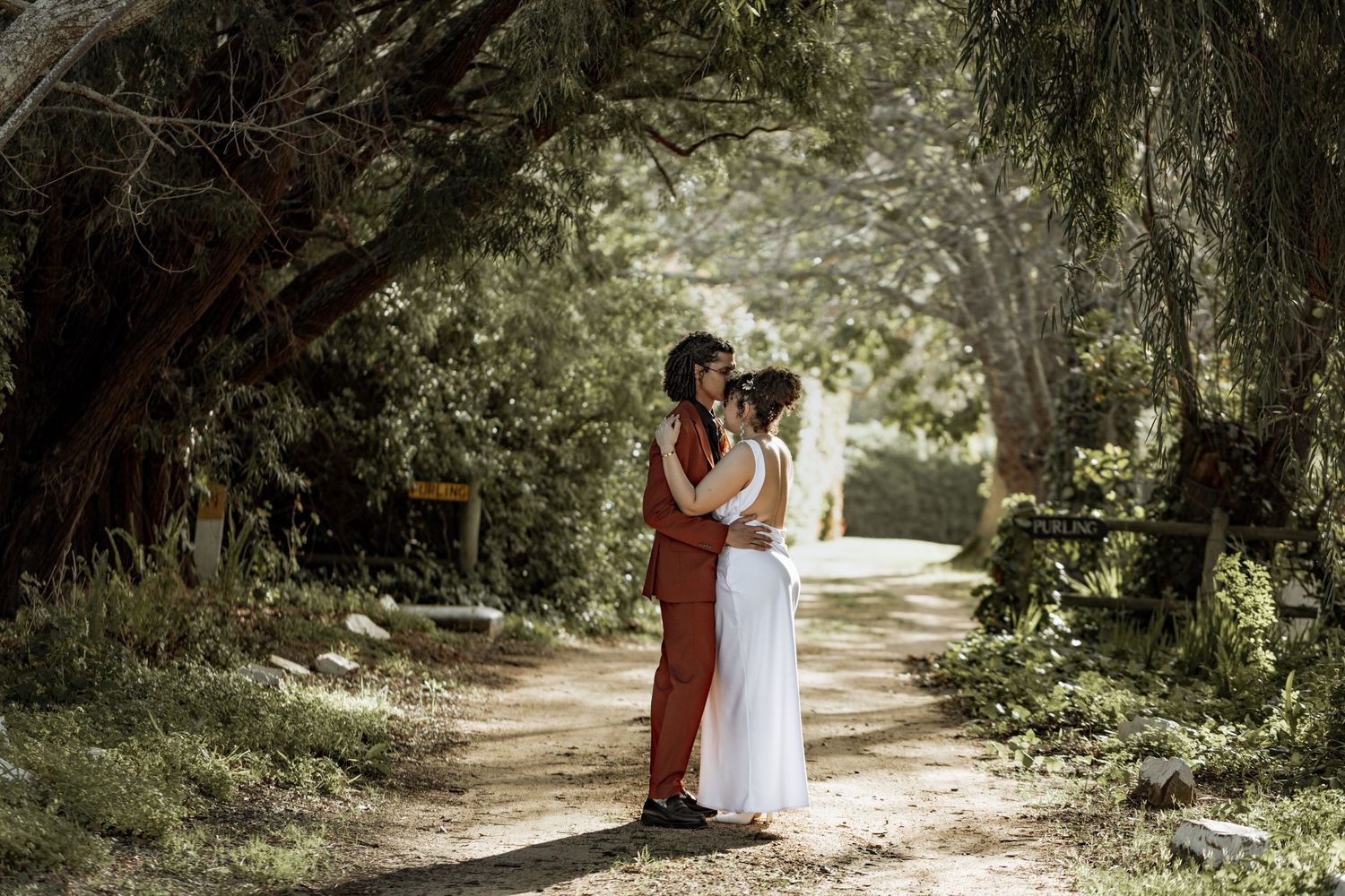 A romantic photo series of a couple in formal attire walking together through a sunlit wooded path.