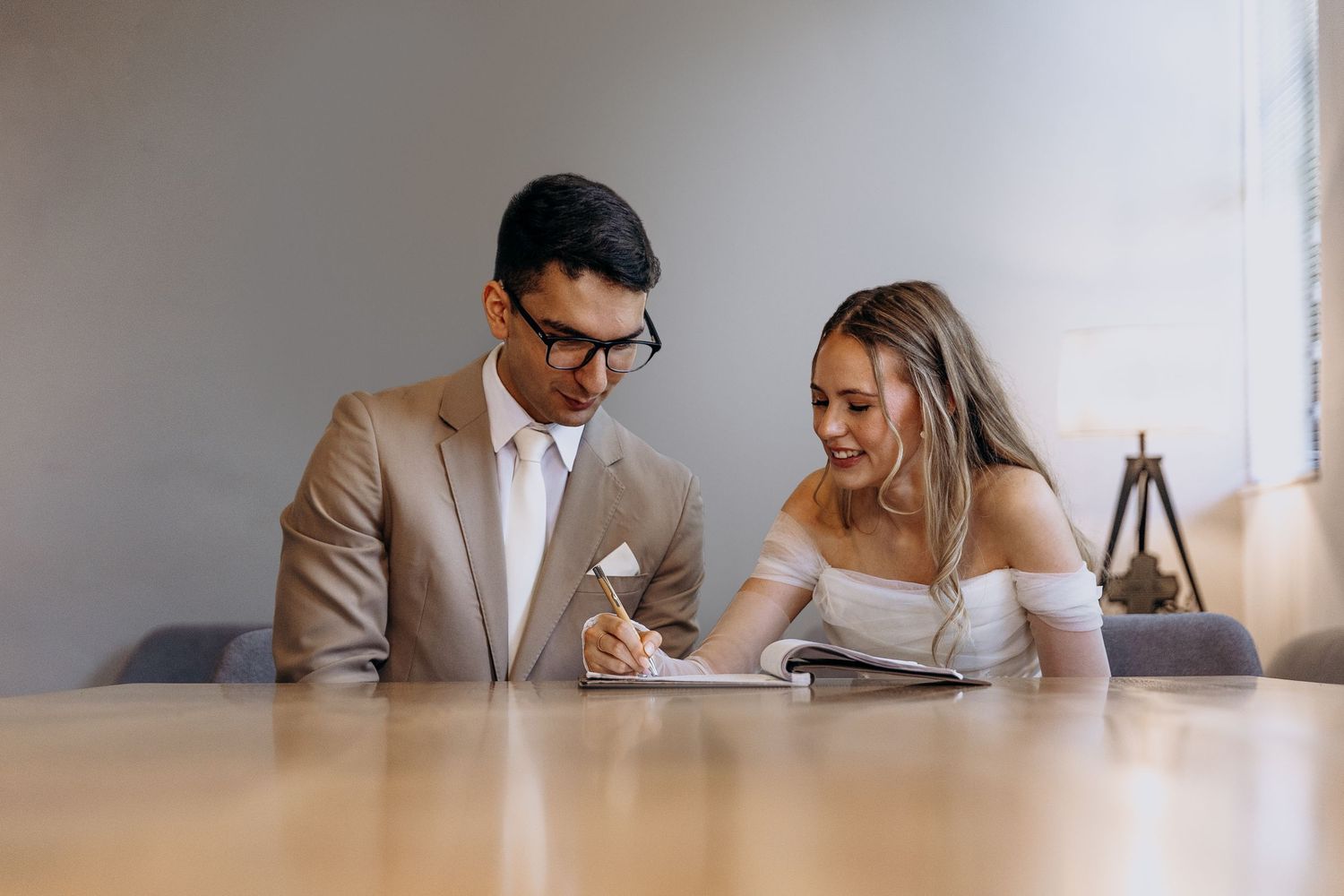 Two people sit at a table in a bright office space reviewing documents together.