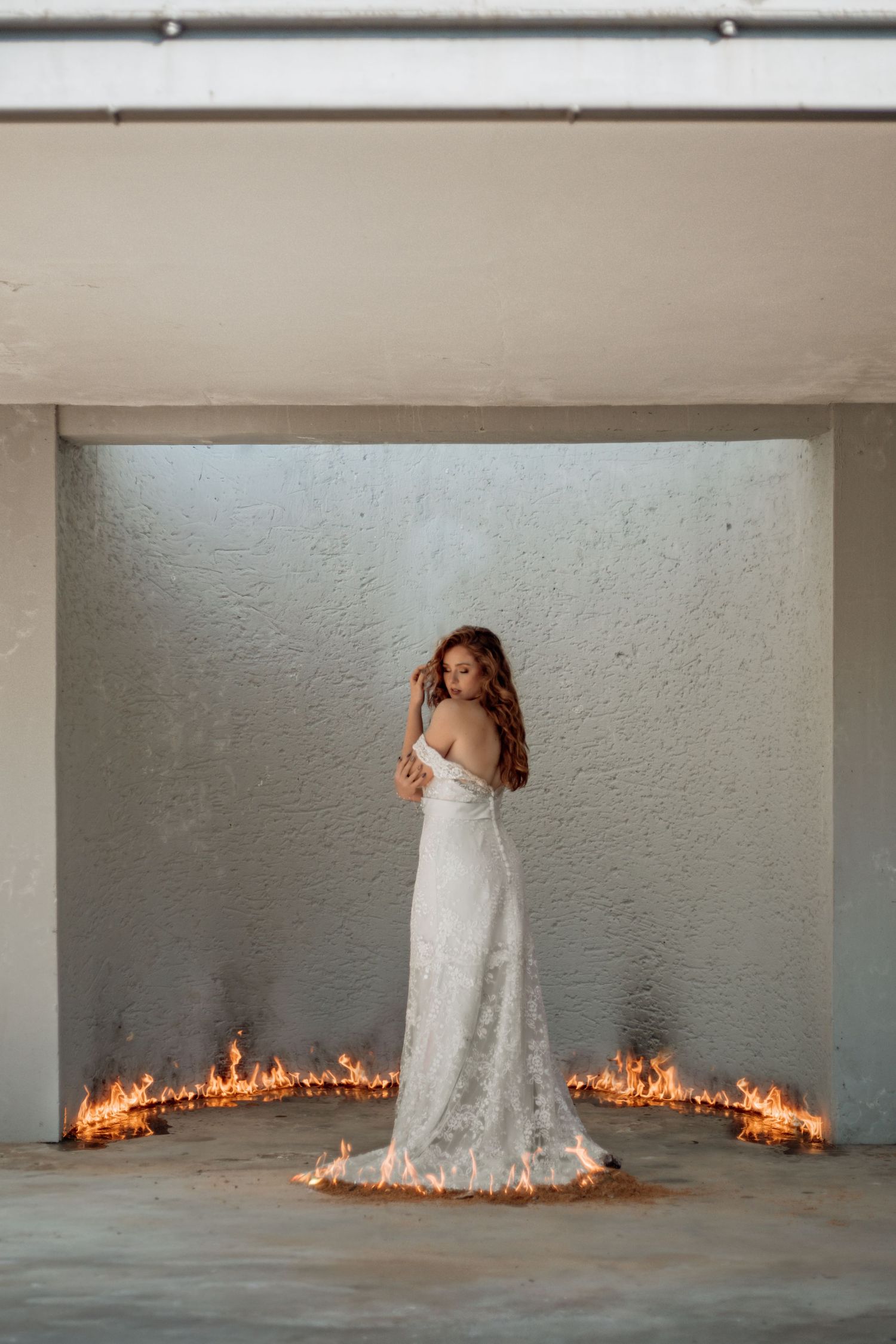 A sequence of photos shows a white dress surrounded by a ring of fire in a stark concrete room.