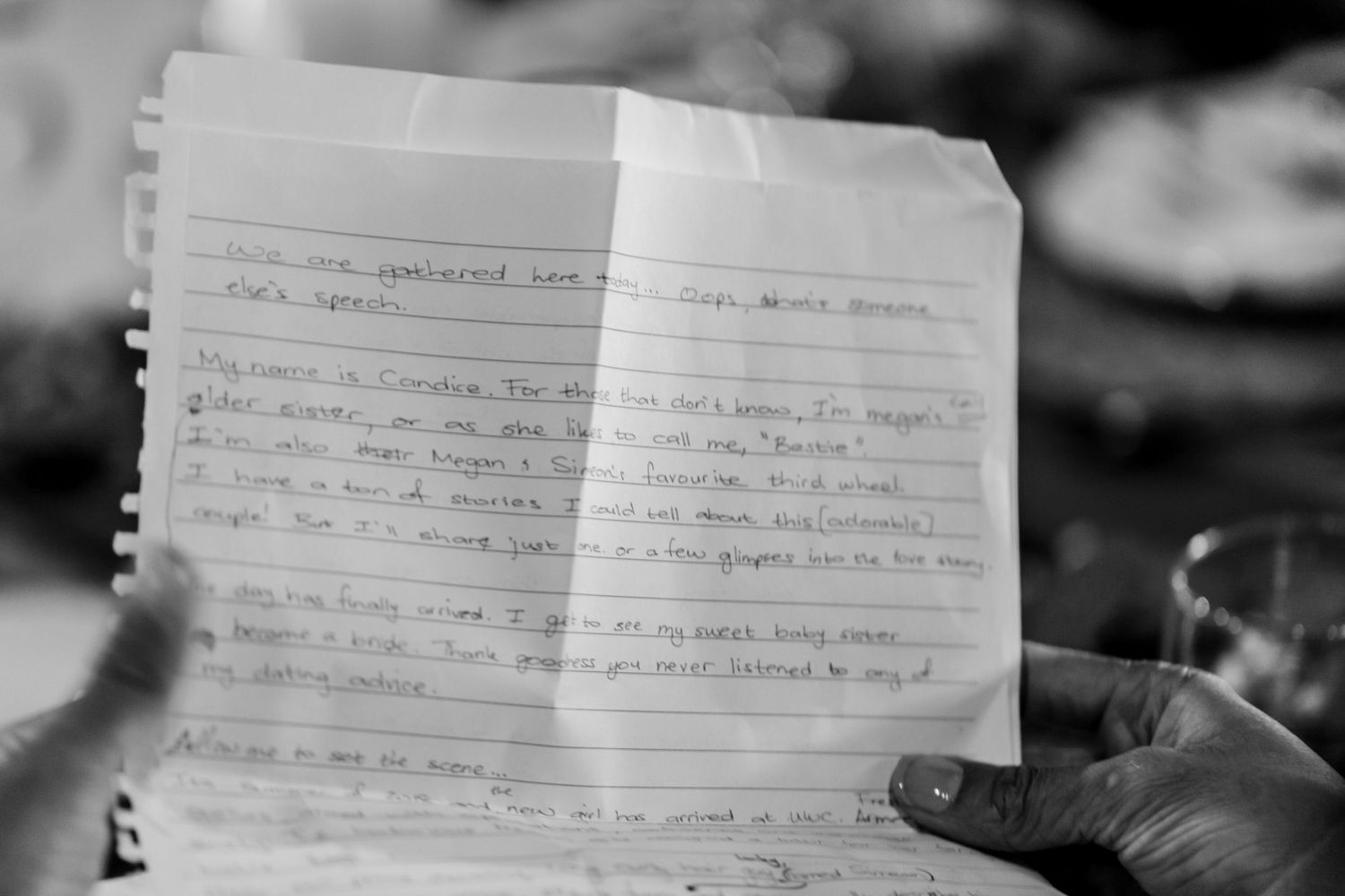 Black and white photo of handwritten notes on lined paper with someone's hand visible holding the page.