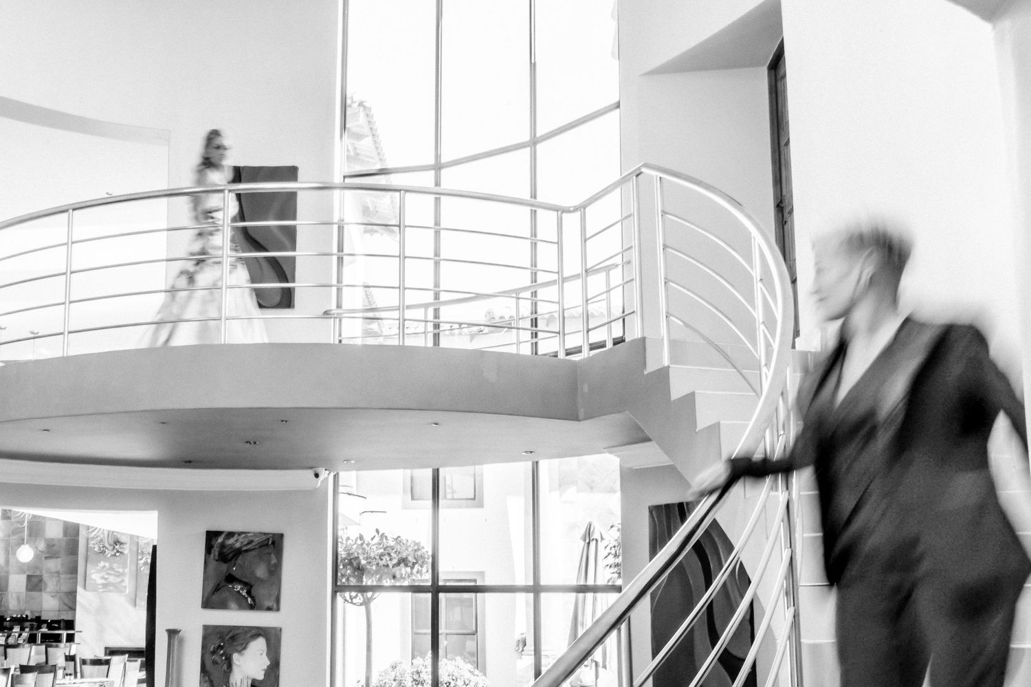 People walking through a modern office building with glass walls and white architectural features in a blurred motion effect.