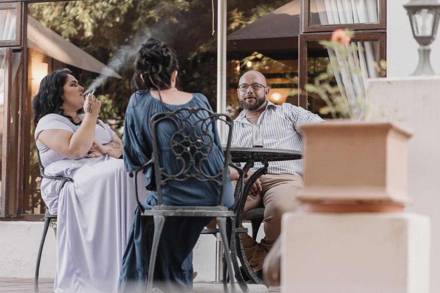 People sit together at an outdoor cafe table having a conversation on a sunny afternoon.
