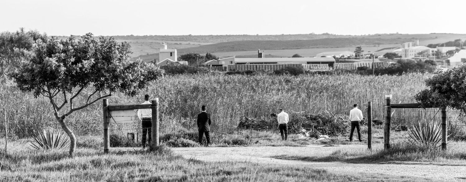 A black and white panoramic landscape photograph shows a vast prairie with scattered buildings and structures.