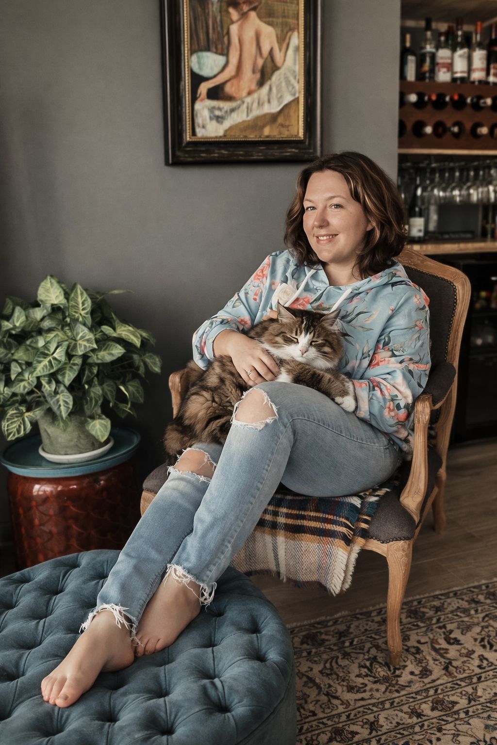 A relaxed scene showing someone lounging in a tufted chair with a cat while surrounded by houseplants and home decor.