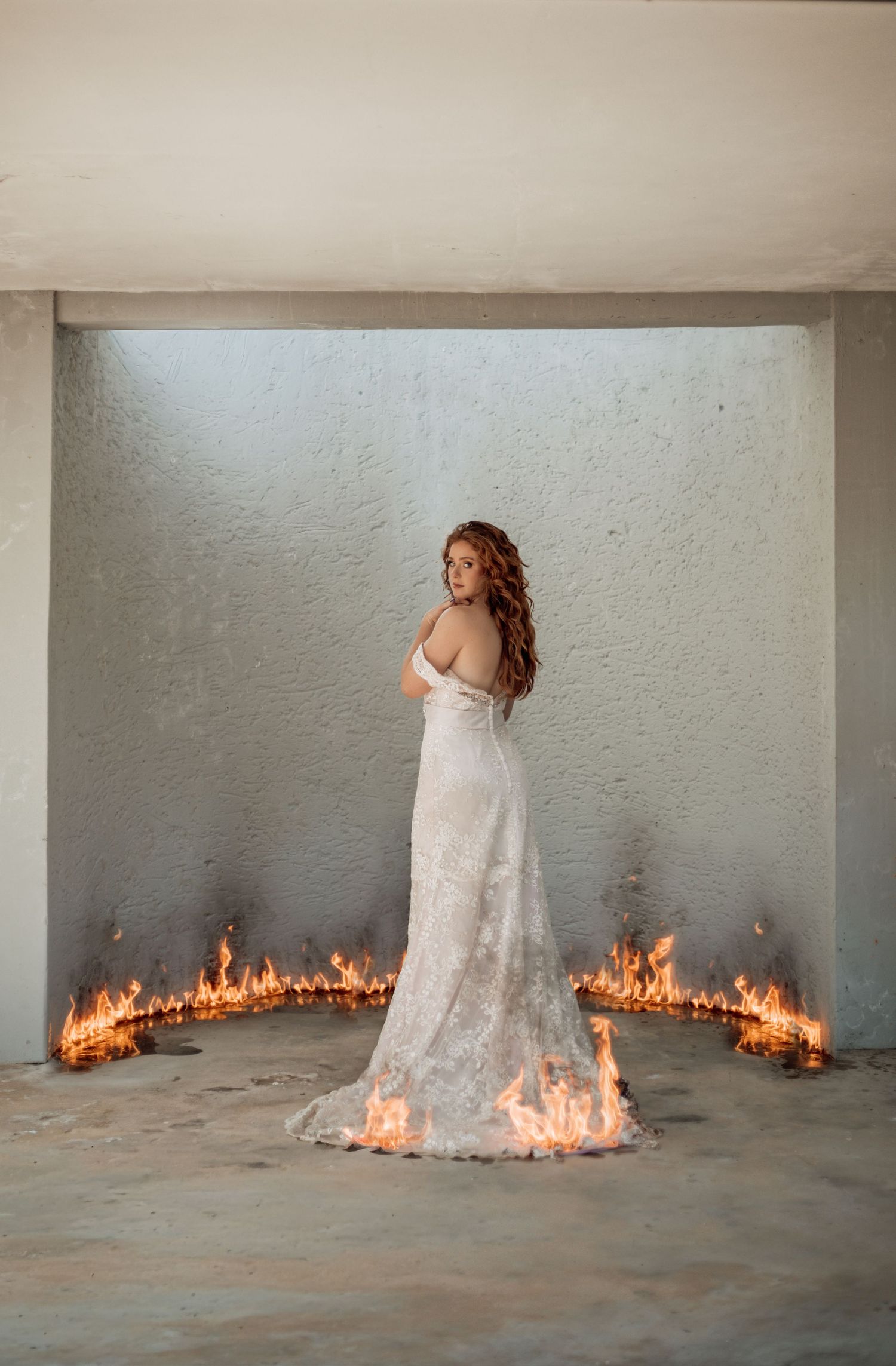 A progressive series of photos showing a white dress against a gray wall with fire spreading along the bottom edge.