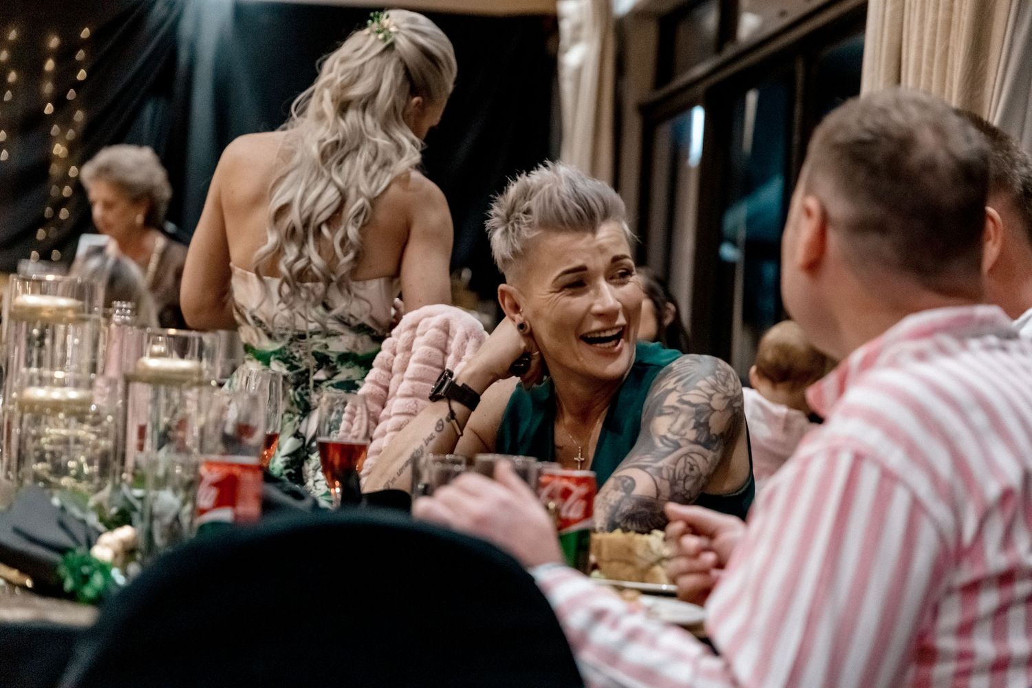 A group of people enjoying a festive dinner party with wine glasses and laughter around a dining table.