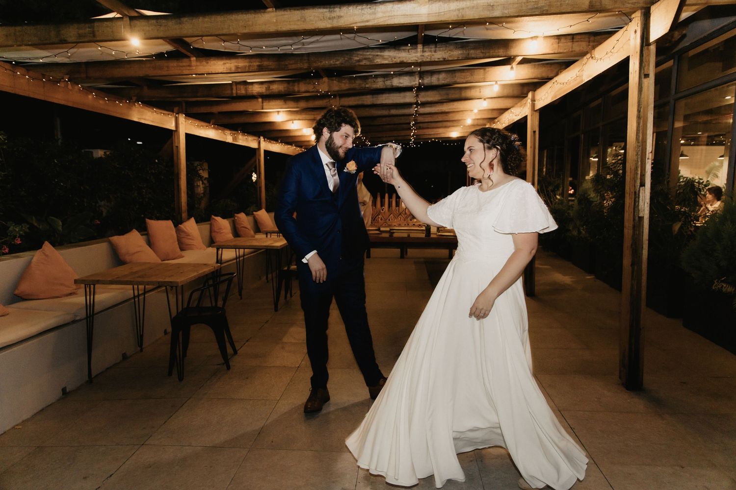 A couple dancing together in a rustic indoor venue with warm lighting and wooden floors.