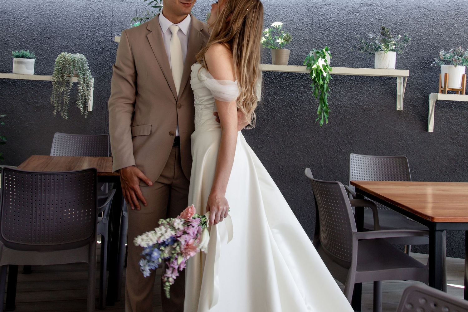 Bride and groom share intimate moments during their wedding photoshoot in a modern restaurant setting.