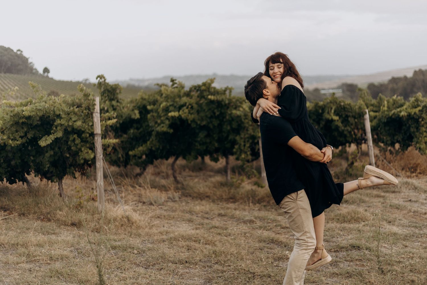 A couple embraces in a romantic photoshoot across multiple scenic outdoor locations at sunset.