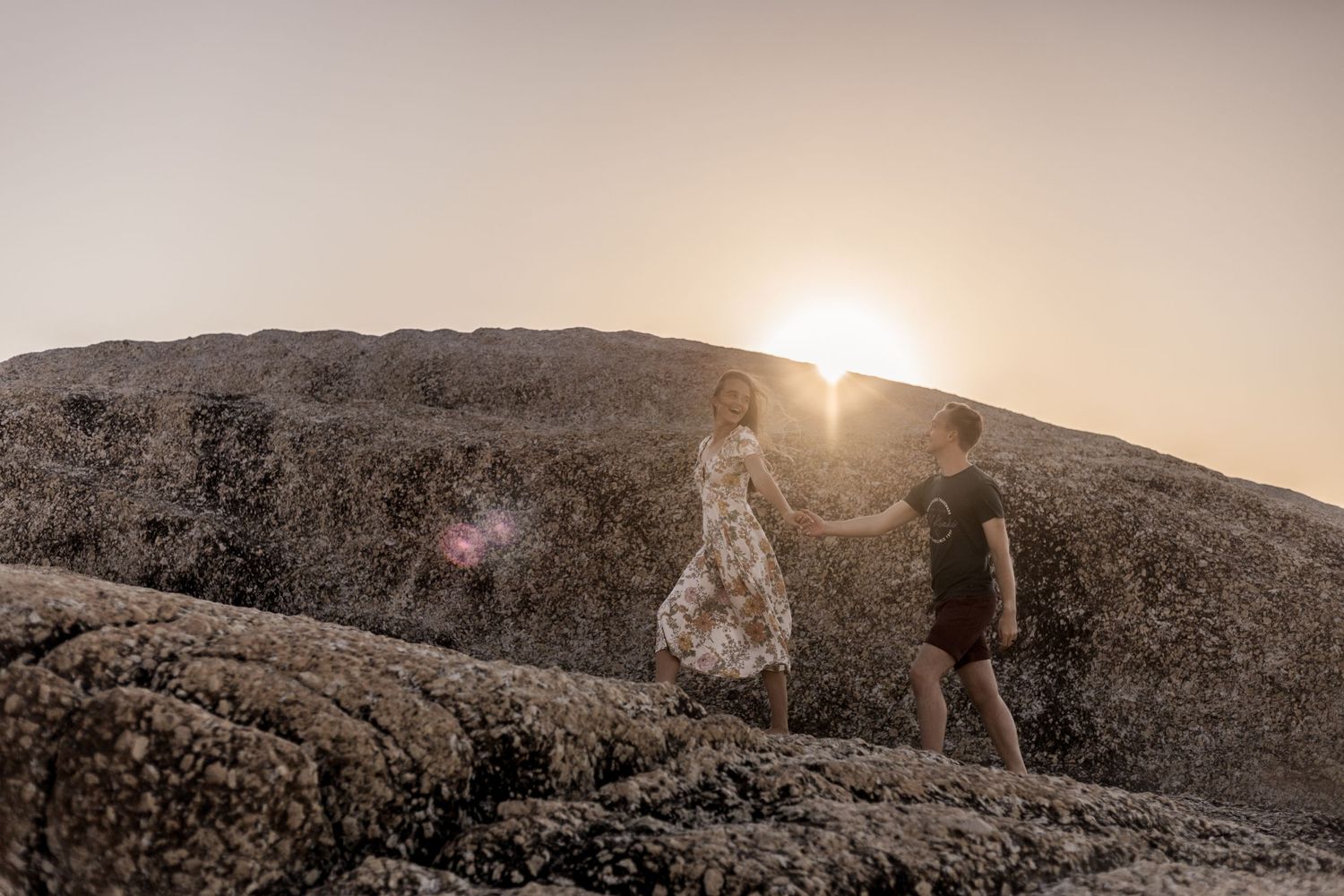 Silhouettes of people walking along a mountain ridge against a golden sunset sky.
