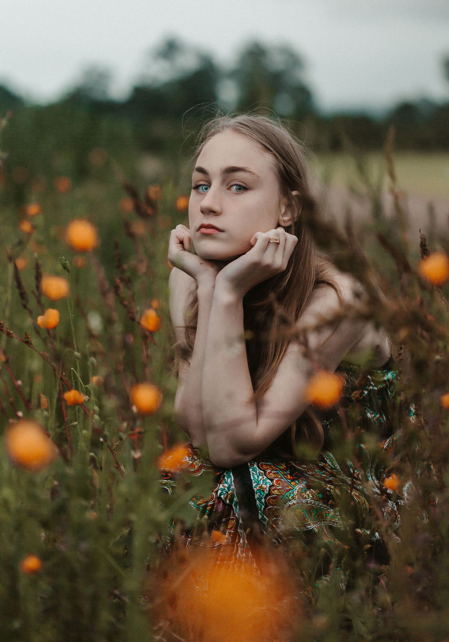 Artistic portrait in a wildflower field with orange blooms creating a dreamy atmosphere at golden hour.