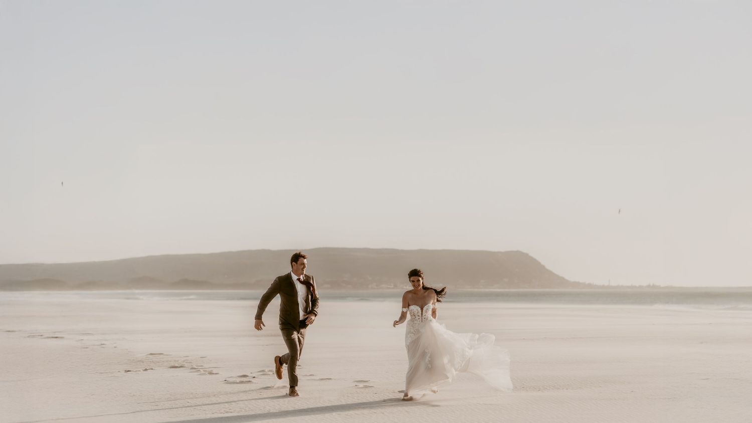 A series of five vintage-style sepia photographs showing a couple walking and dancing together on a misty beach.