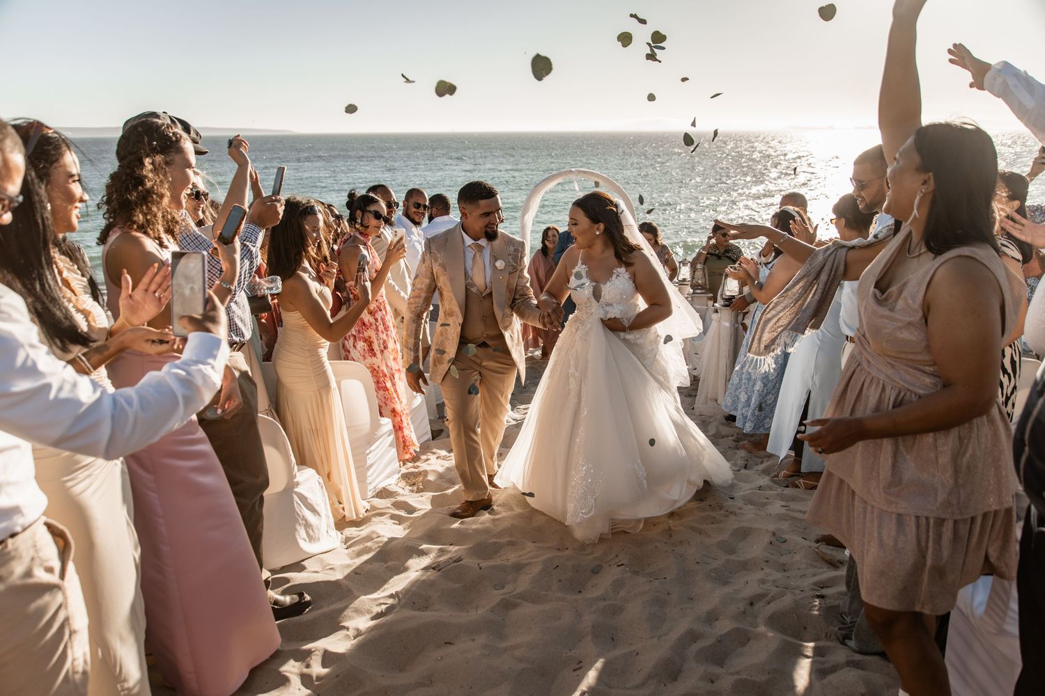 Wedding guests toss birdseed and confetti into the air as the couple exits through a celebratory walkway.