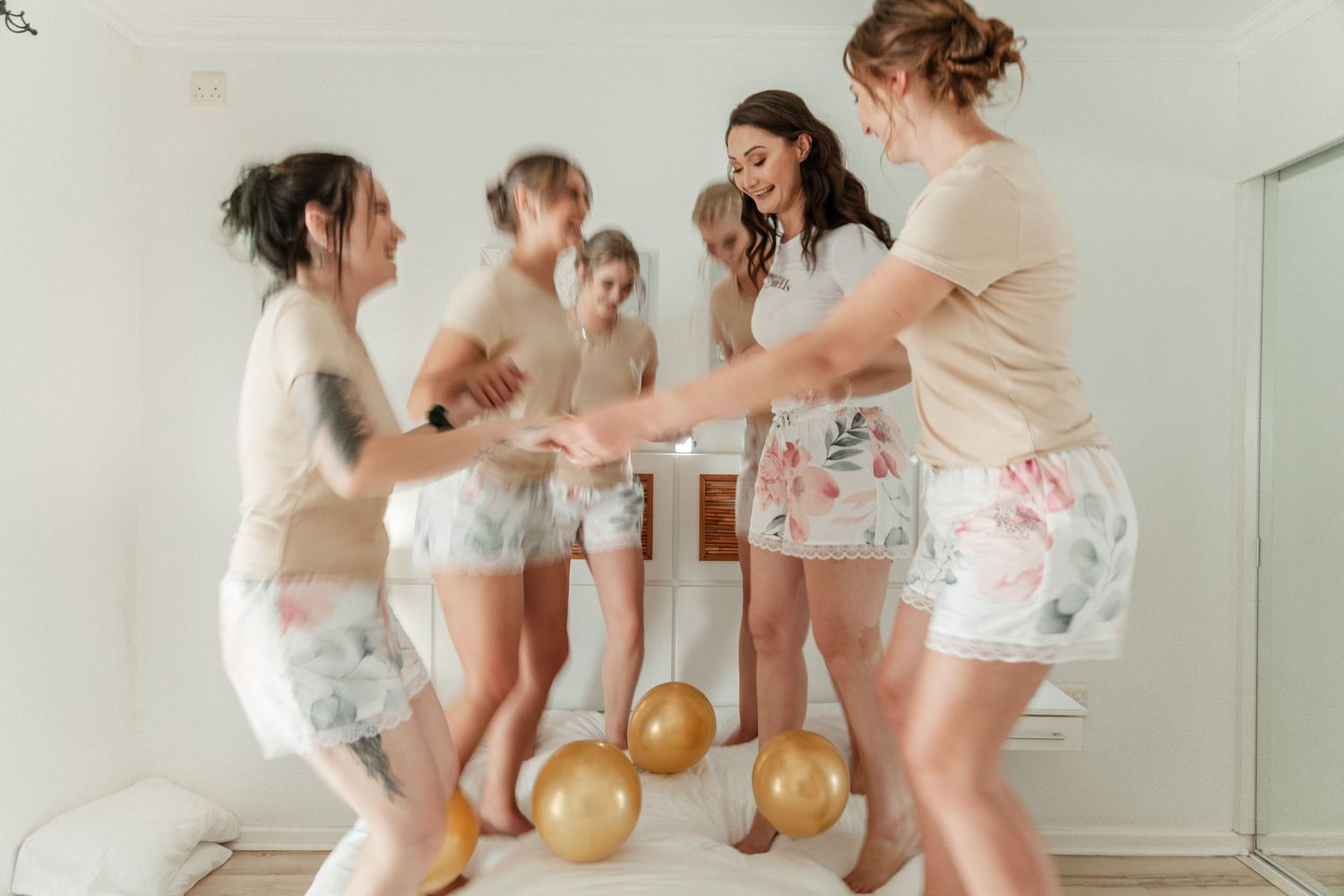A group of people in white sleepwear having fun and laughing together during a slumber party celebration.